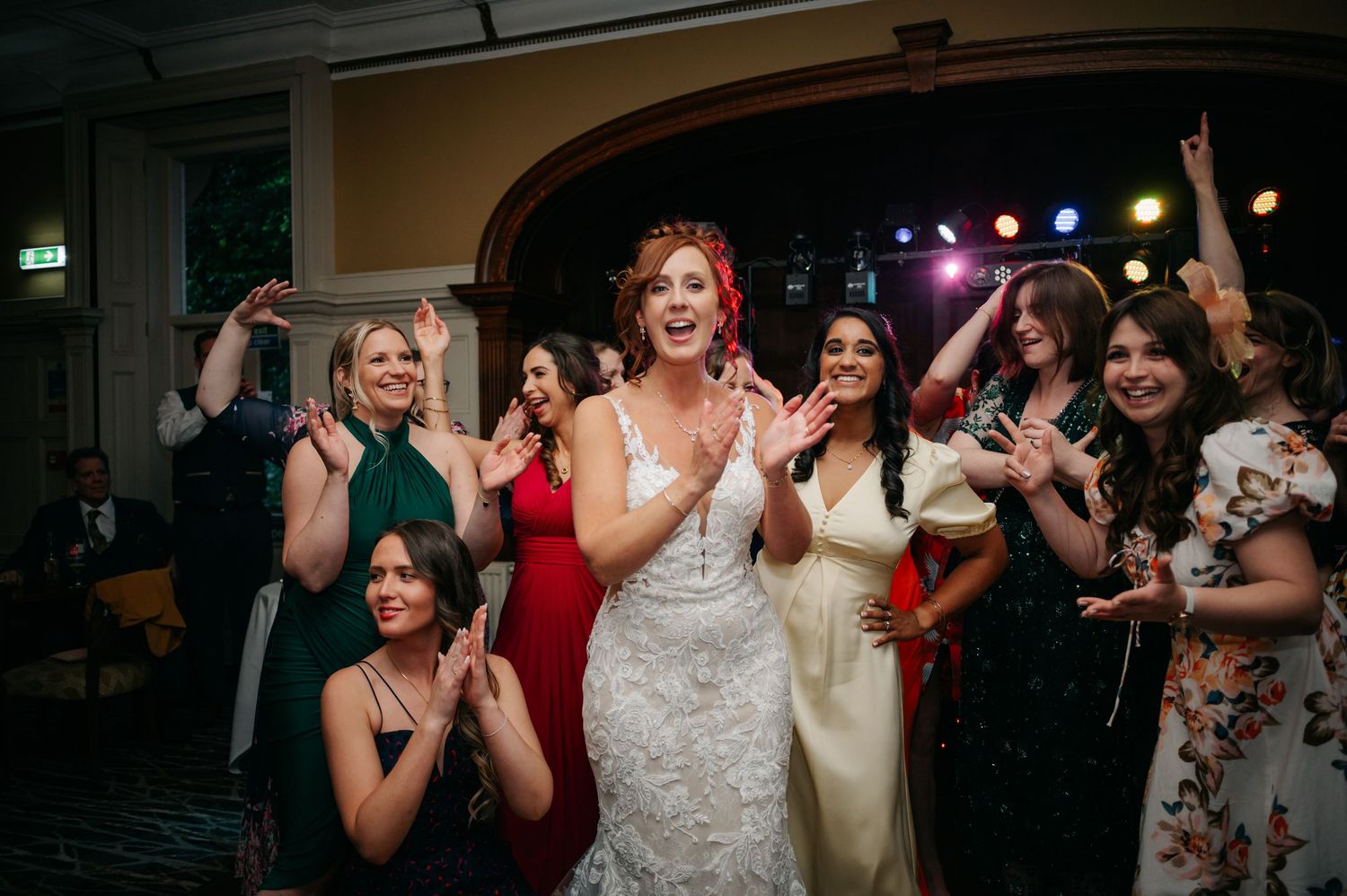 Wedding guests dancing and celebrating on the dance floor during evening reception.