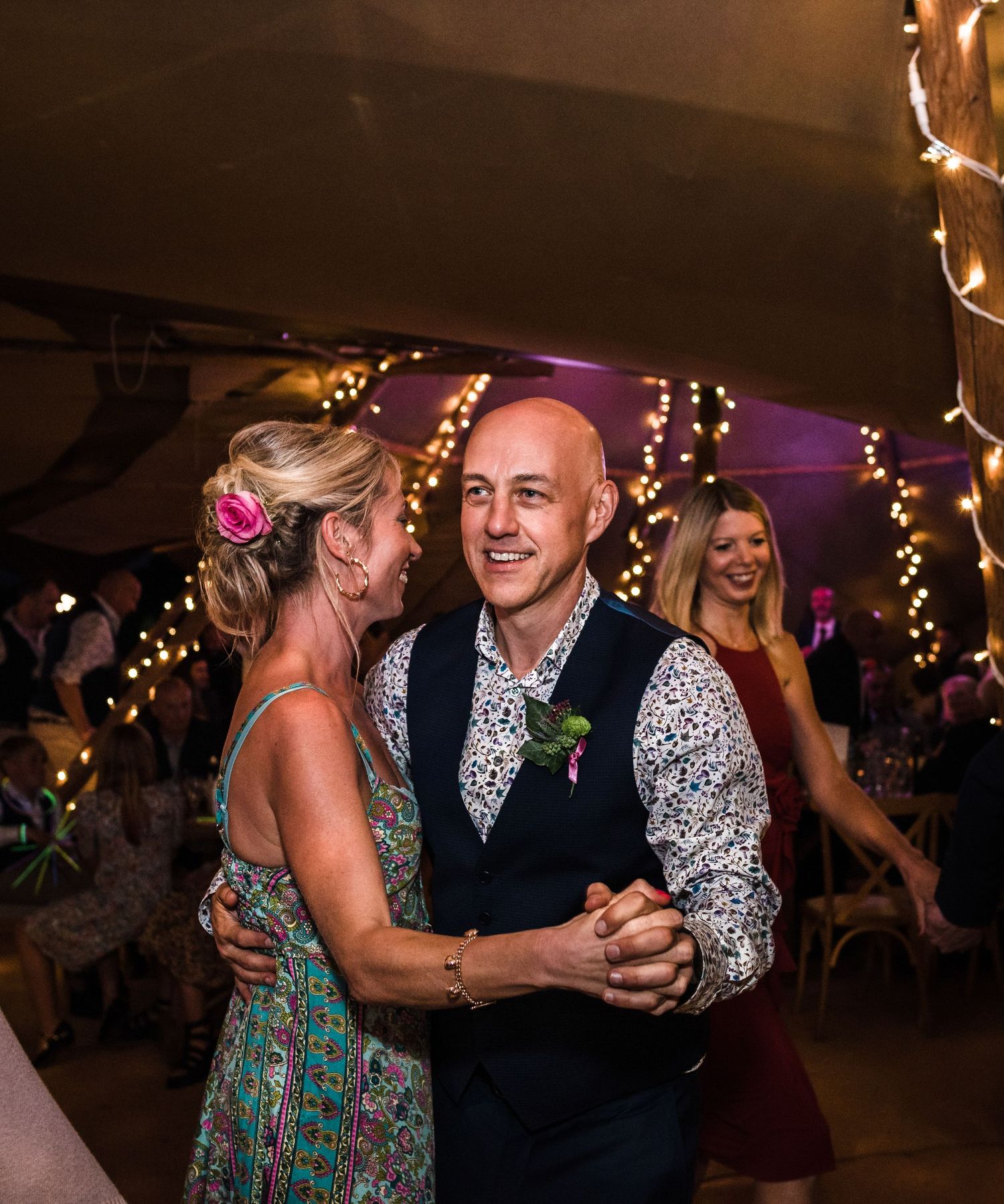 Couples dancing at a wedding reception under twinkling lights.