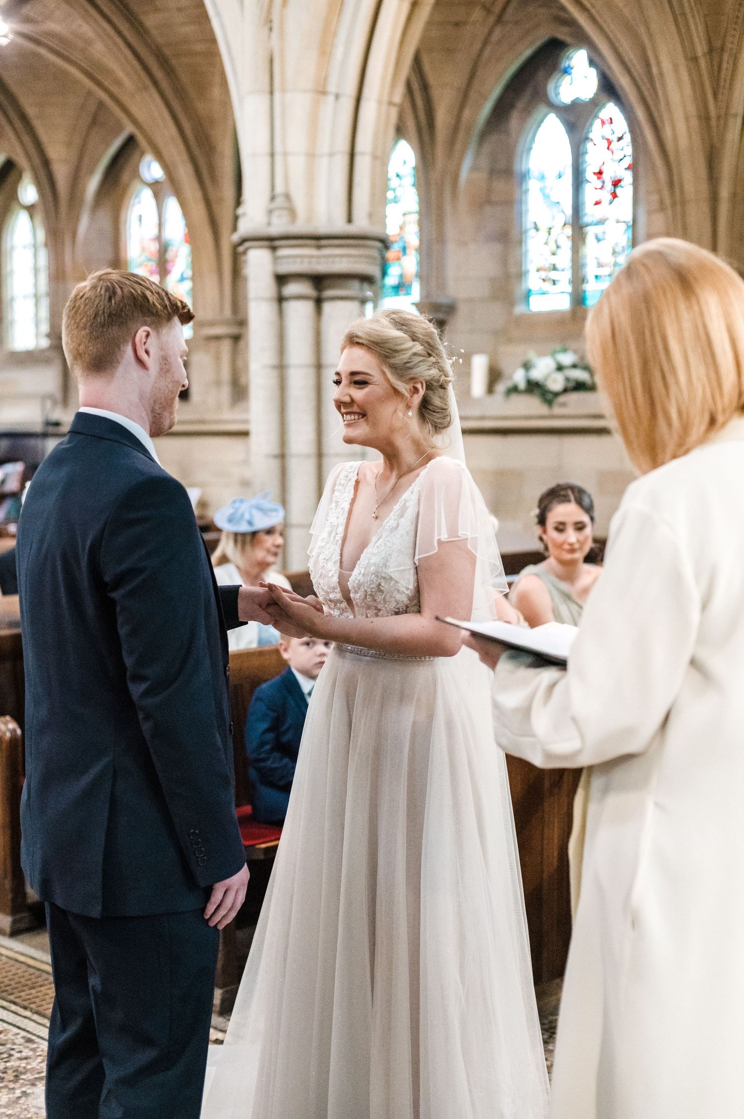 A wedding ceremony taking place in a beautiful gothic church with stained glass windows.