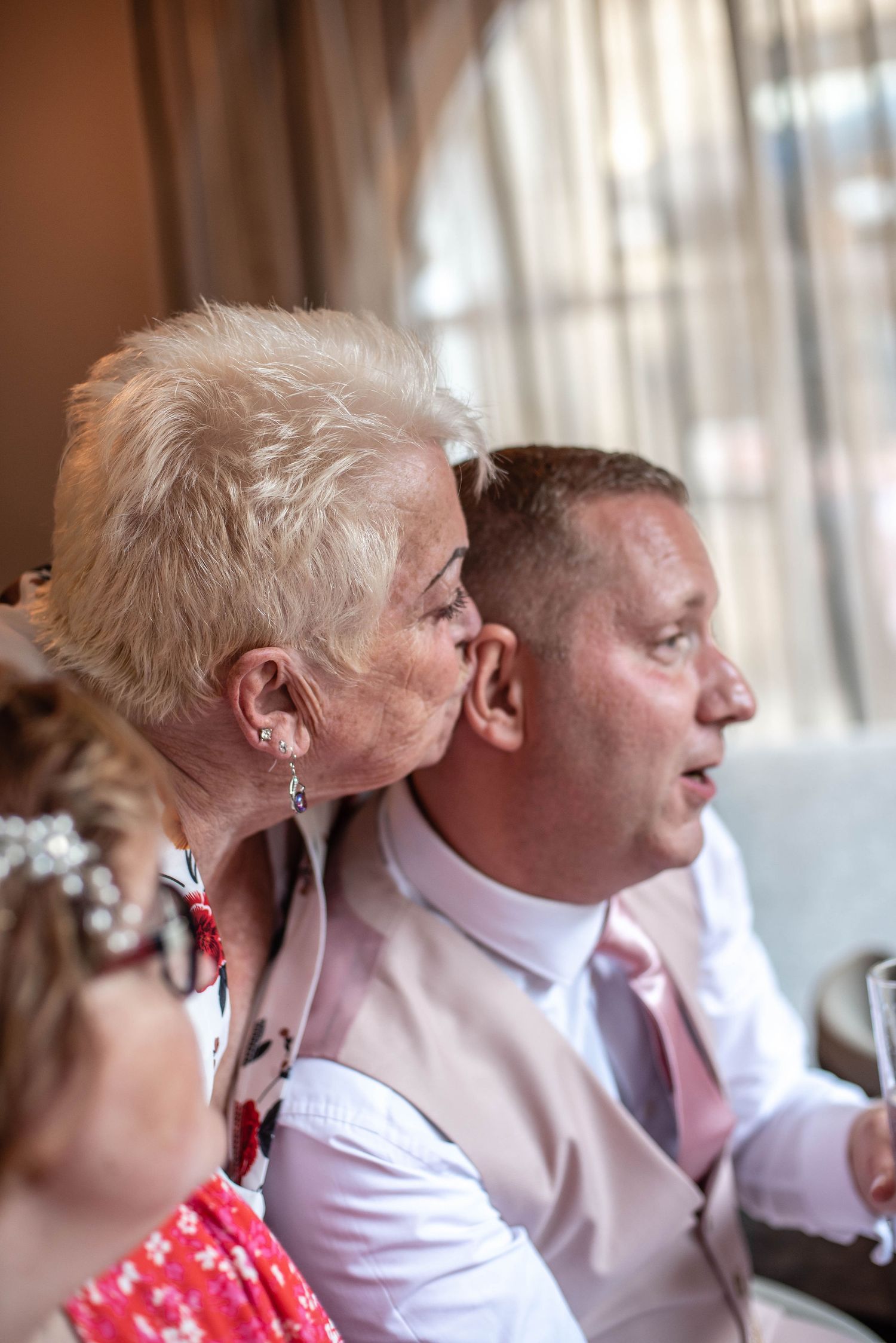 A tender moment between guests during a wedding celebration indoors.