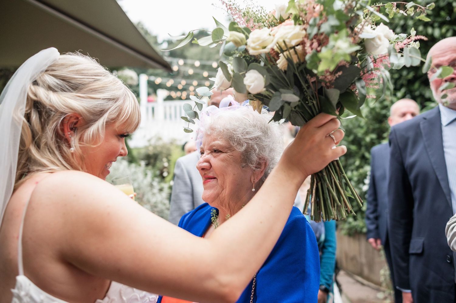 Emotional embrace shared during outdoor wedding celebration with floral arrangements.
