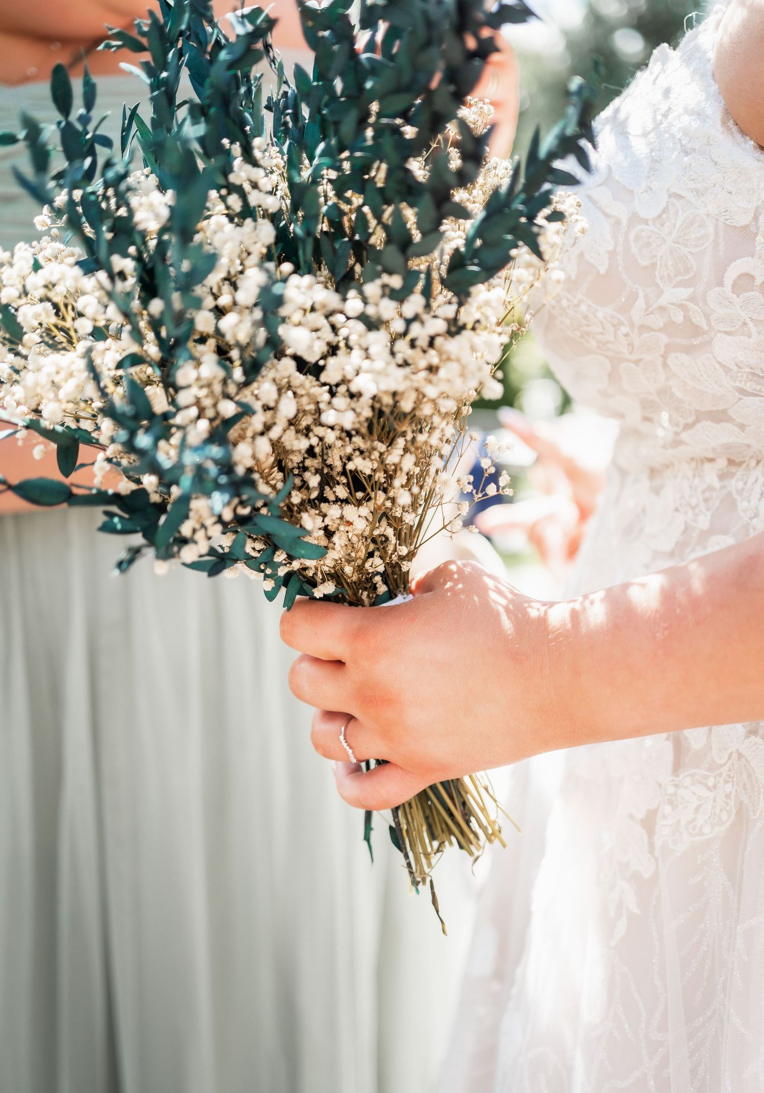 Close-up of a wedding bouquet with white dried flowers and dark green foliage.