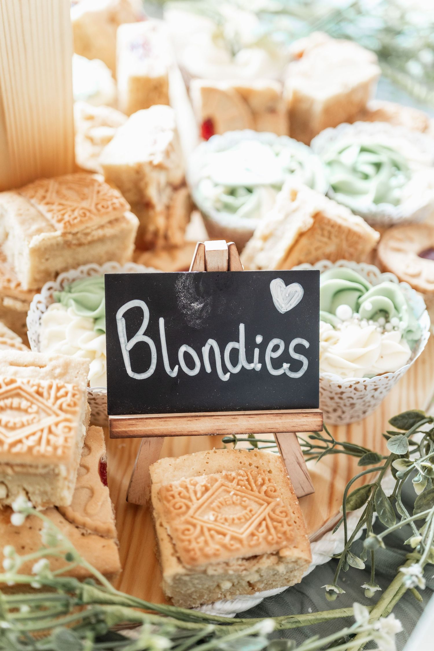 Wedding dessert display featuring blonde brownies with a decorative chalkboard sign and mint green garnishes.