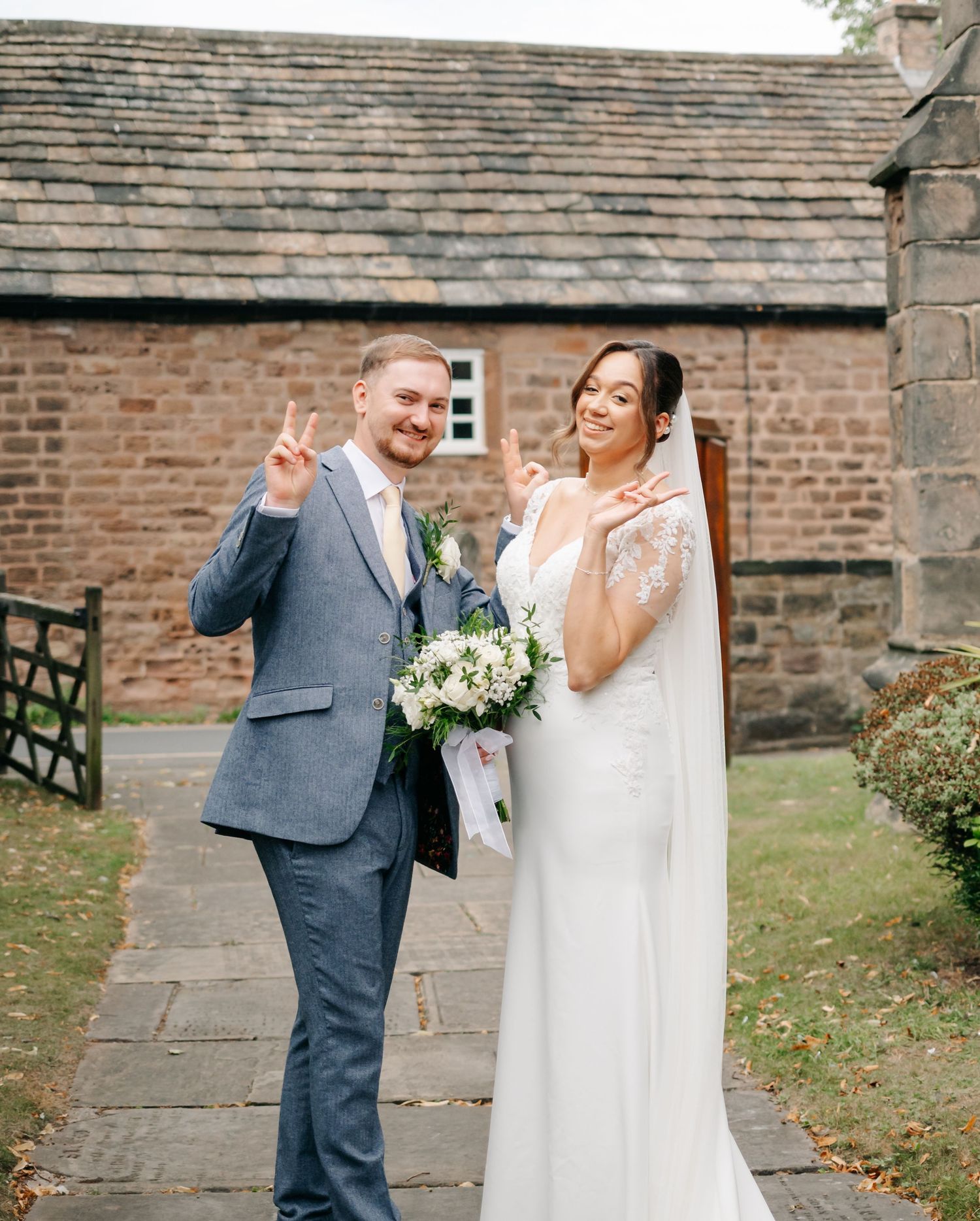 Joyful wedding photos taken outside a rustic brick church building.