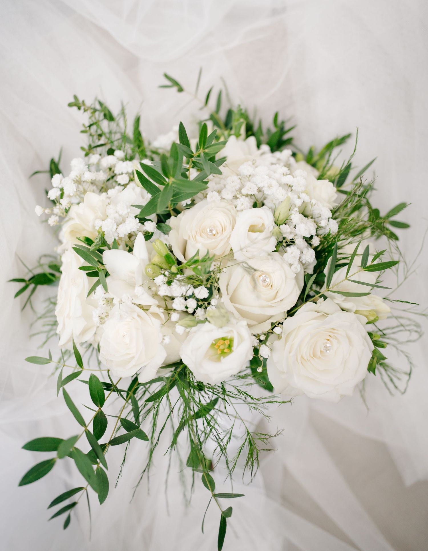 Elegant white rose and greenery floral arrangements displayed in a series of wedding bouquets.