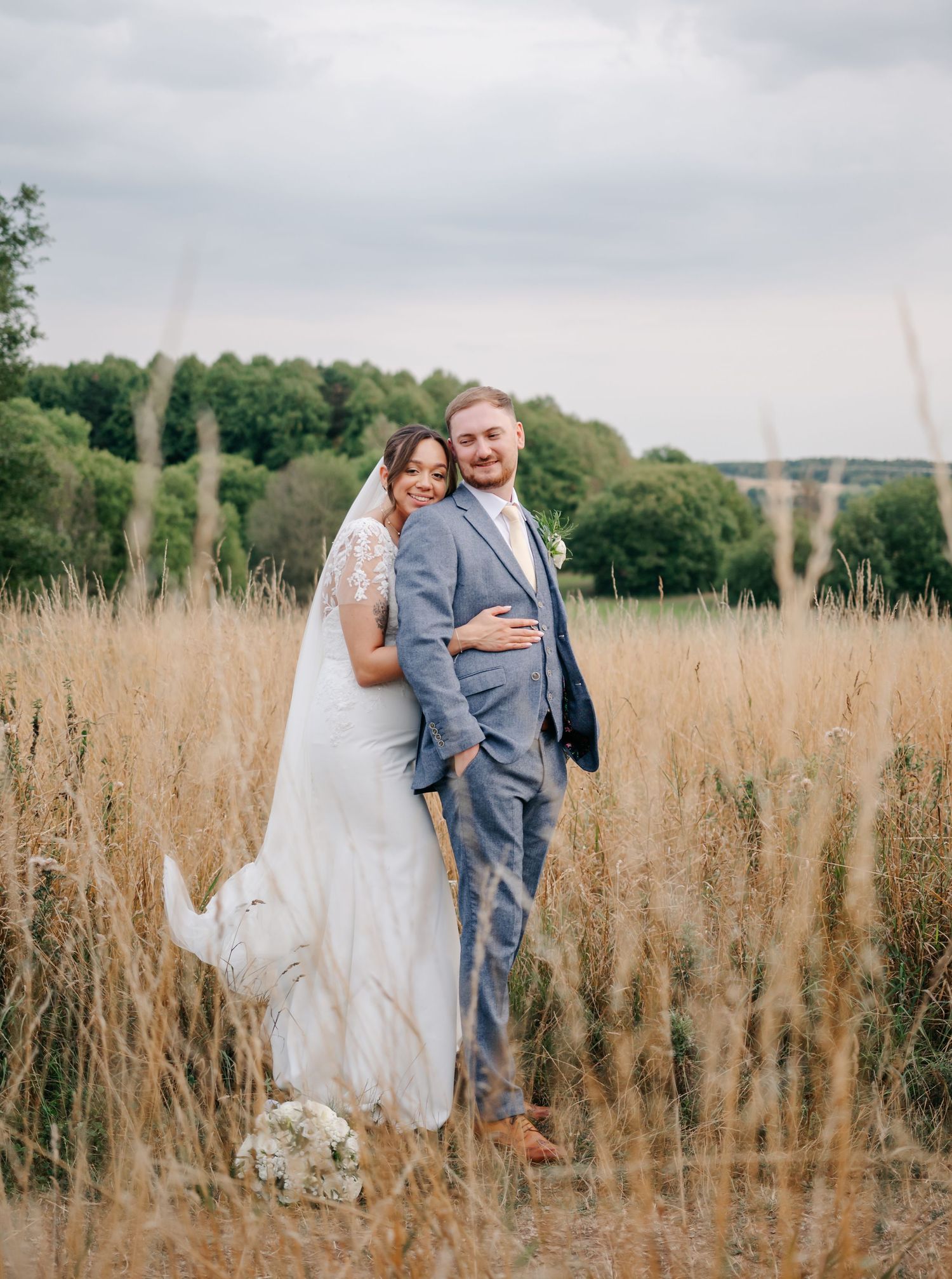 A couple shares a romantic moment in a field of tall grass on their wedding day.