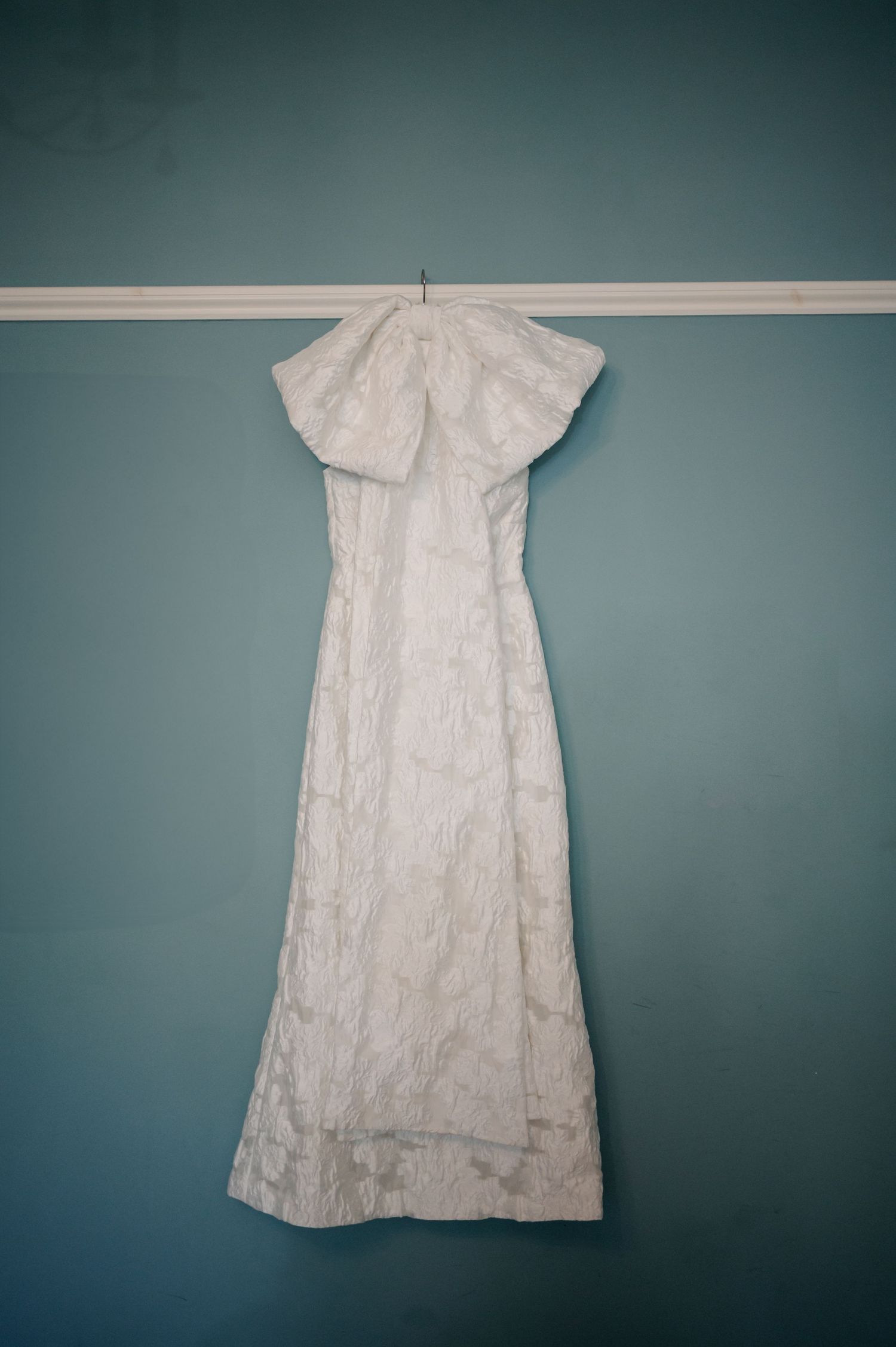 Vintage white christening gown displayed against blue-gray background.