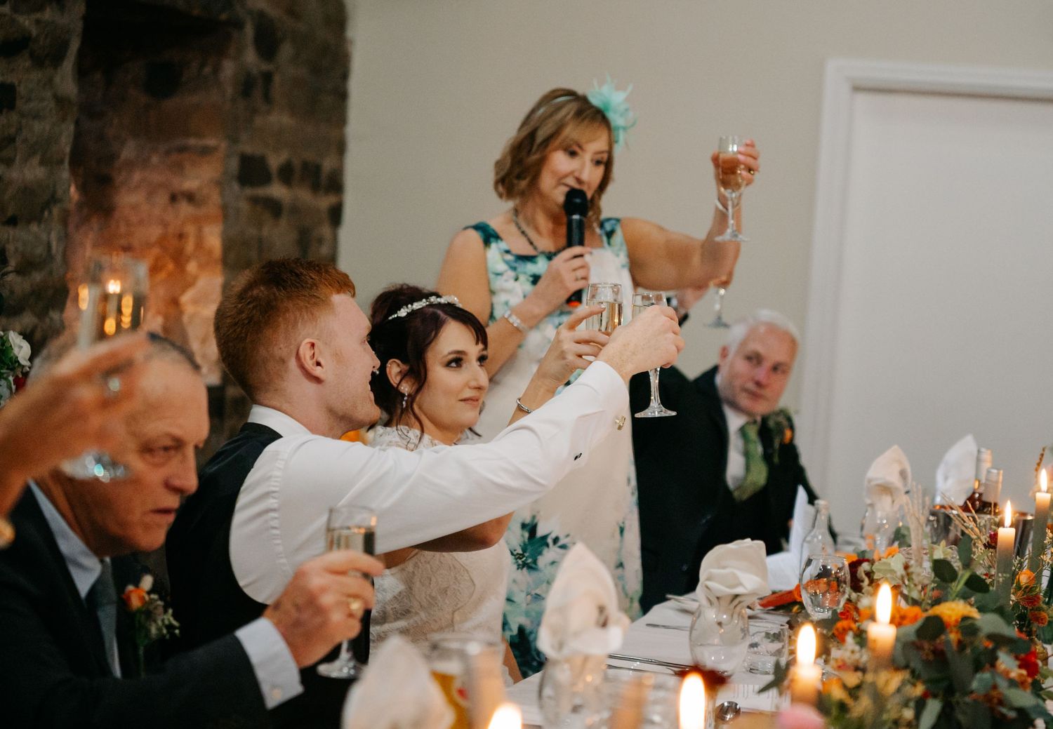 Wedding reception dinner with guests raising toasts by candlelight.