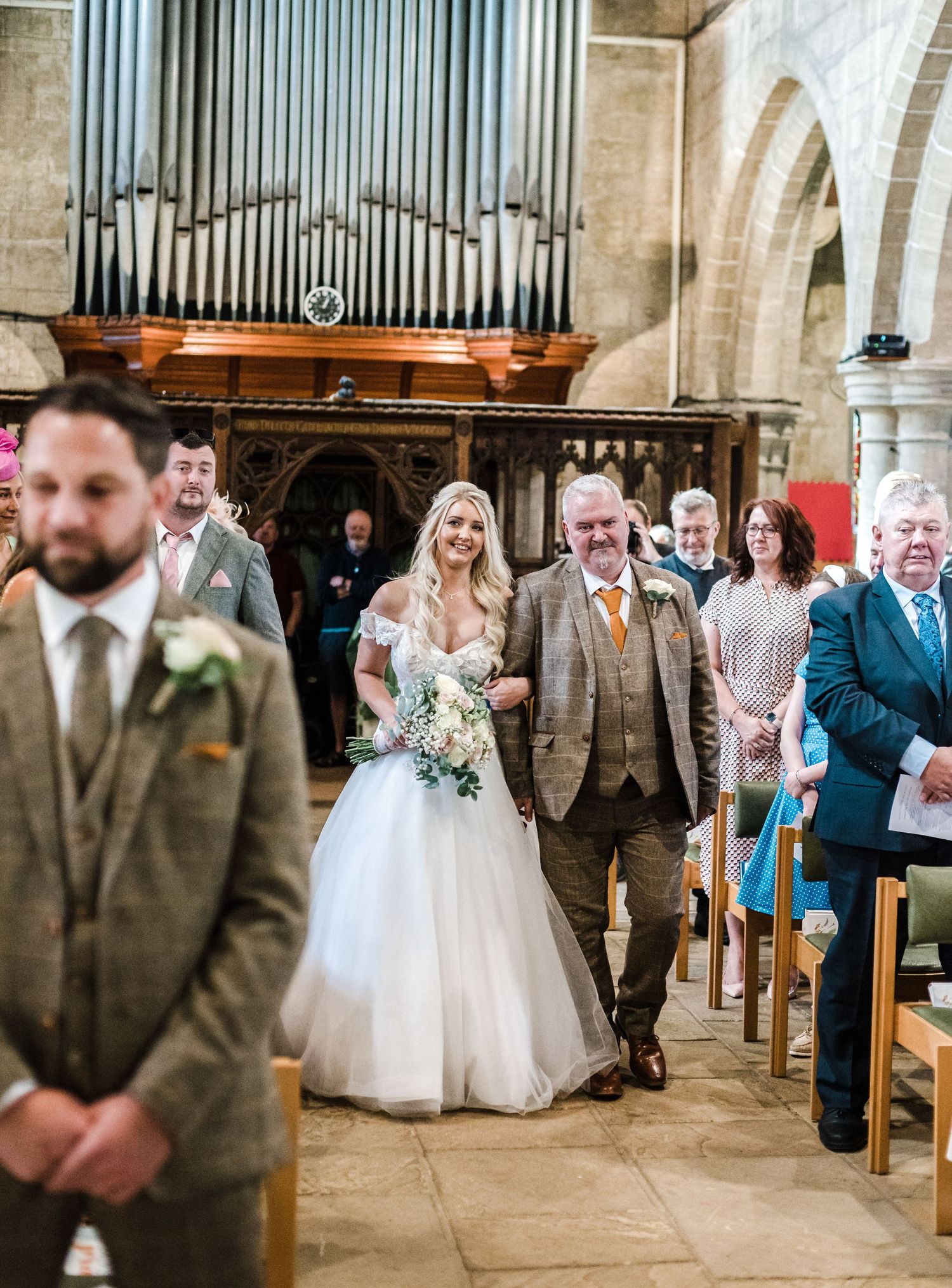 Traditional church wedding ceremony procession with pipe organ and stone archways.