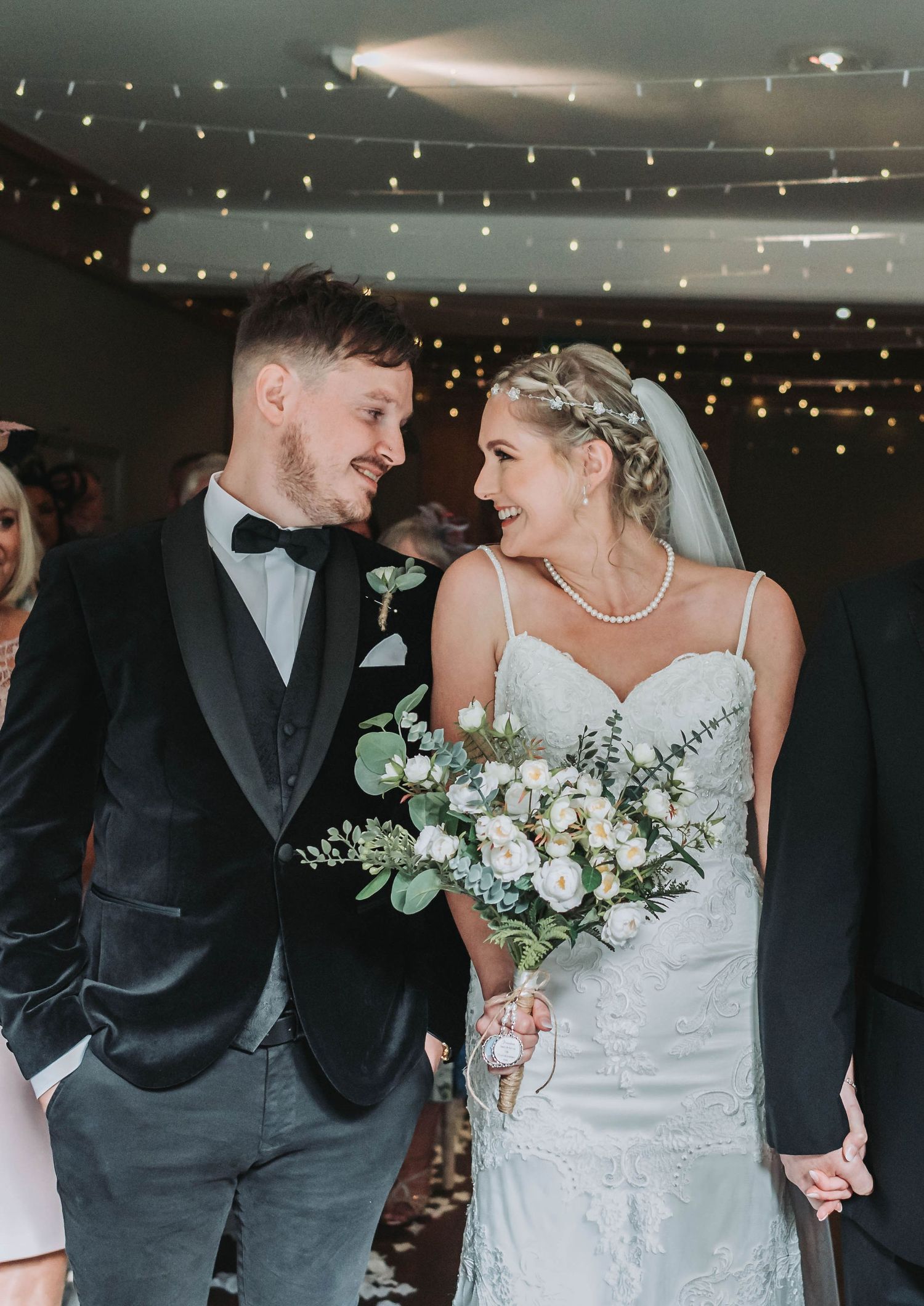 A newlywed couple shares a joyful moment under twinkling lights at their reception.