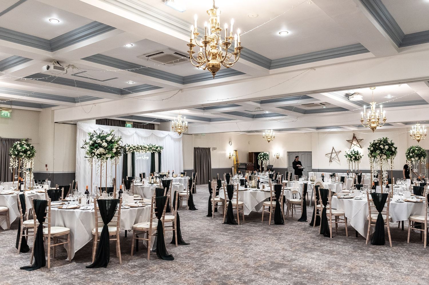 Elegant wedding reception hall with crystal chandeliers and formal table settings.