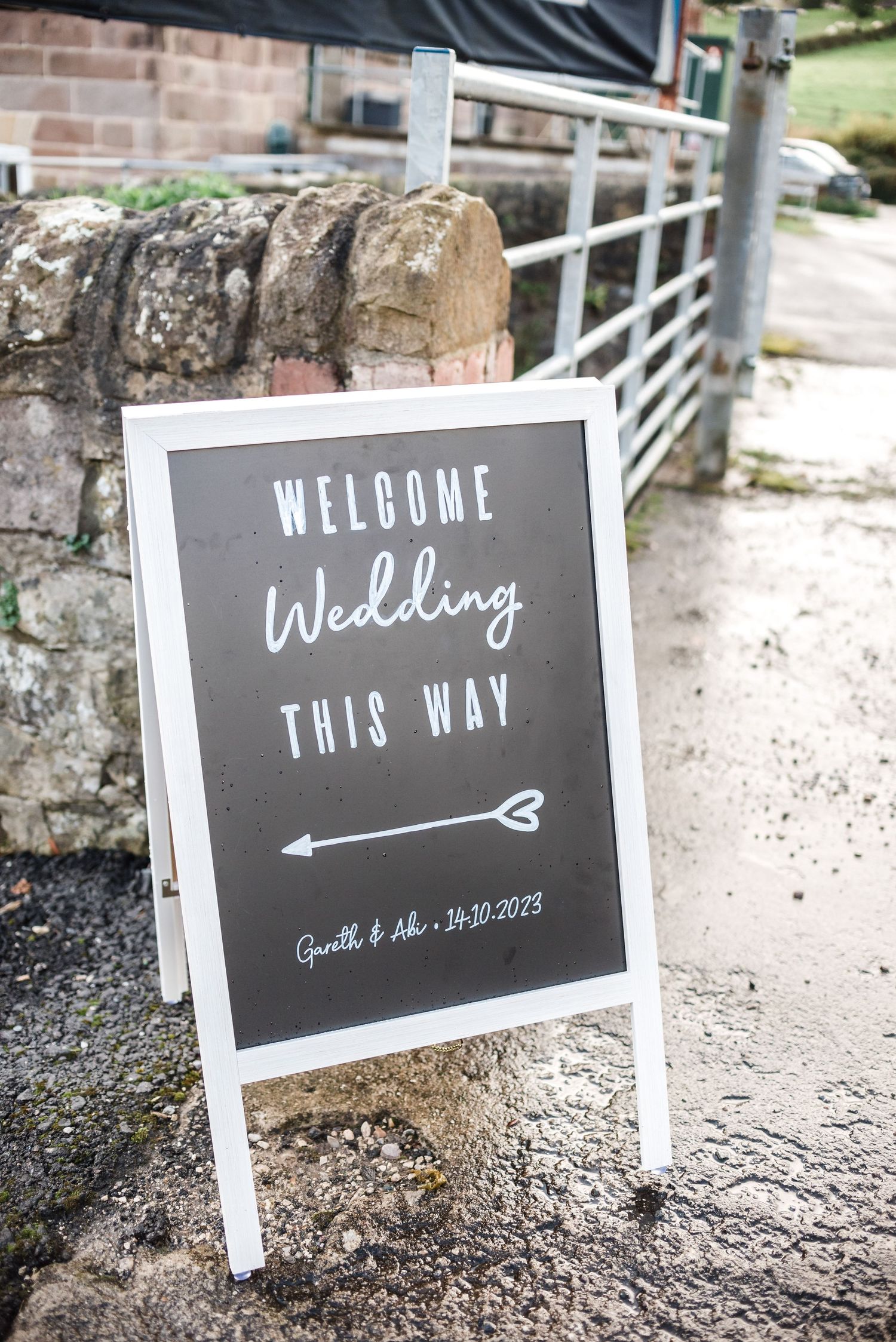 Chalkboard wedding directional sign with arrow on white A-frame stand.