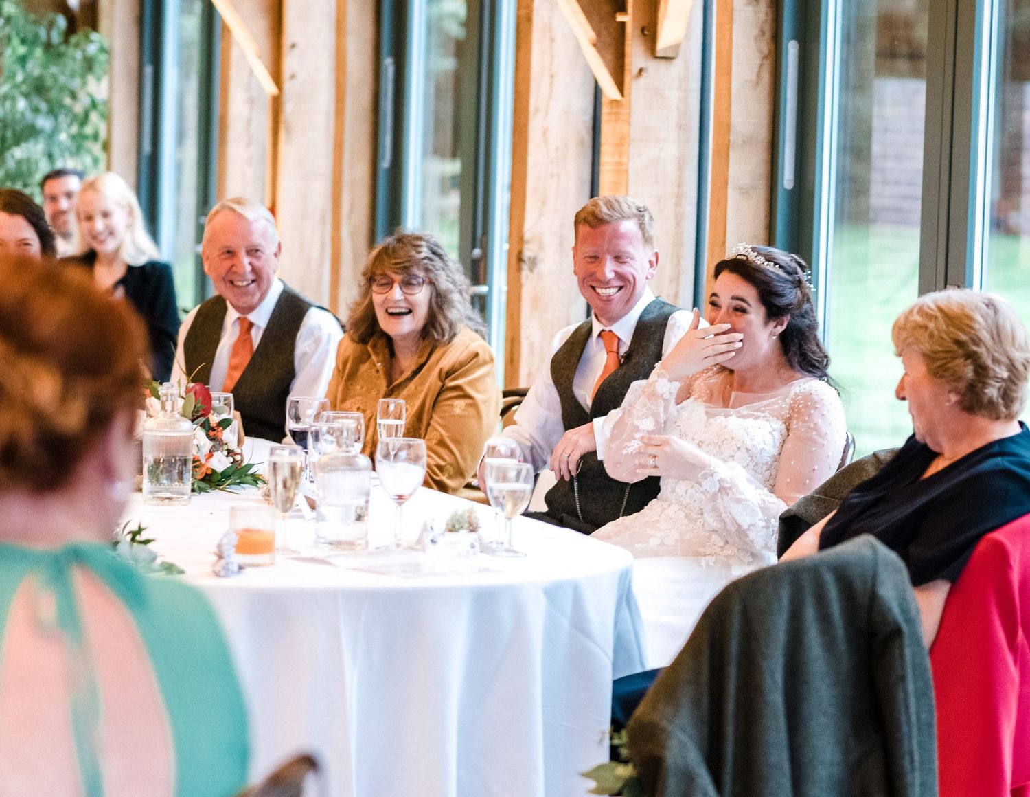Wedding reception guests share joyful laughter during speeches.