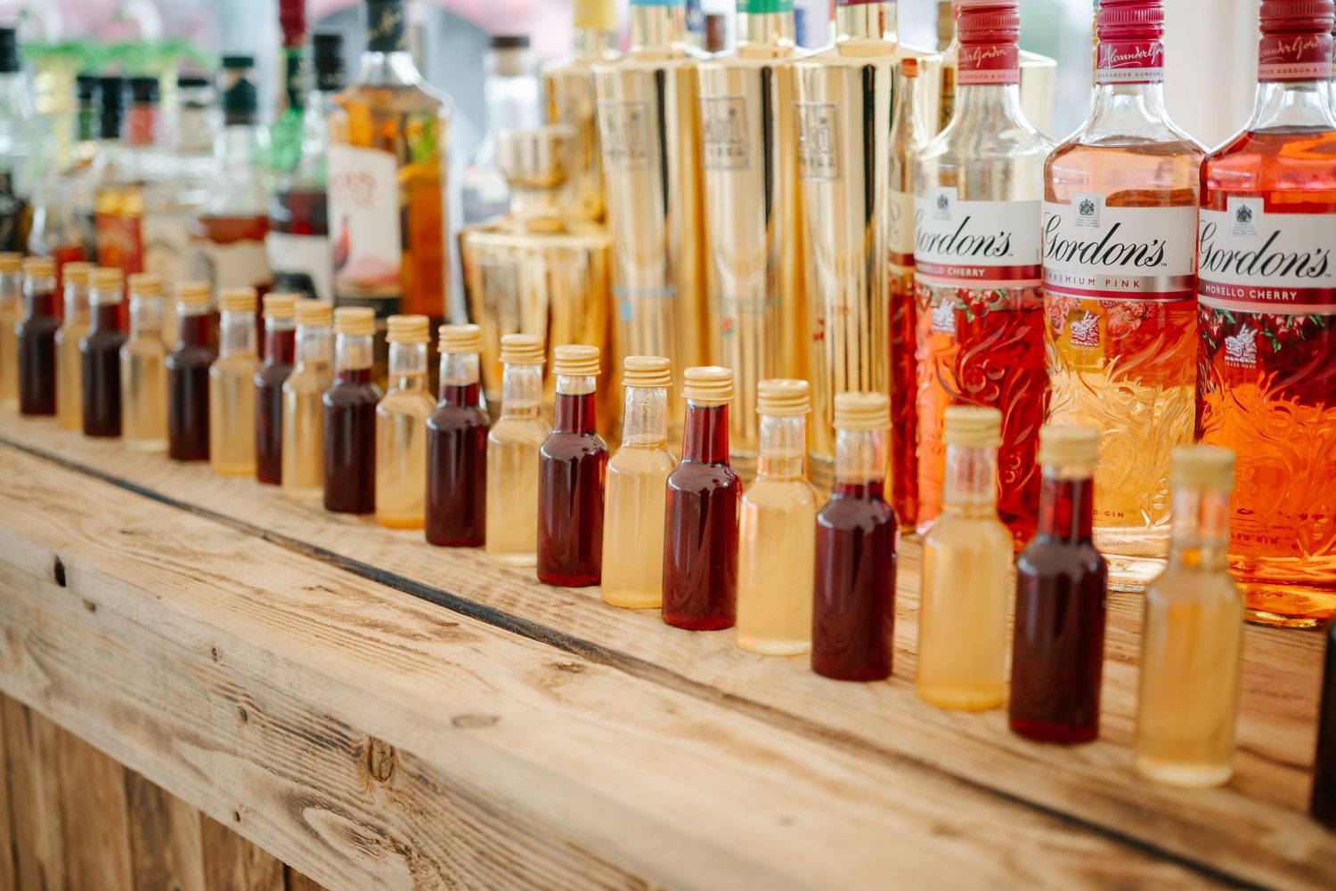 Row of whiskey bottles lined up on a rustic wooden shelf display.