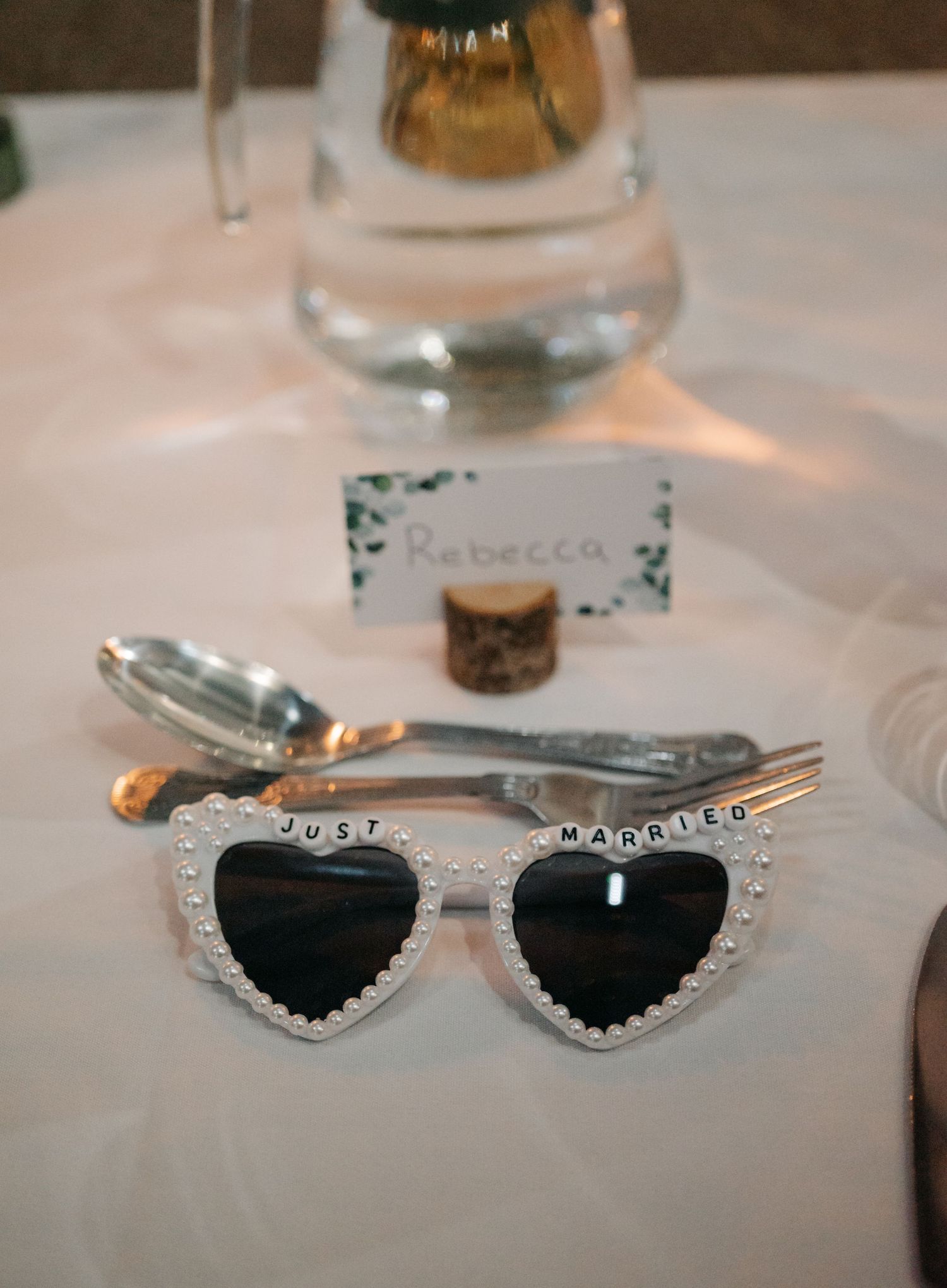 Collection of decorative heart-shaped sunglasses with rhinestone details displayed on white tablecloth.