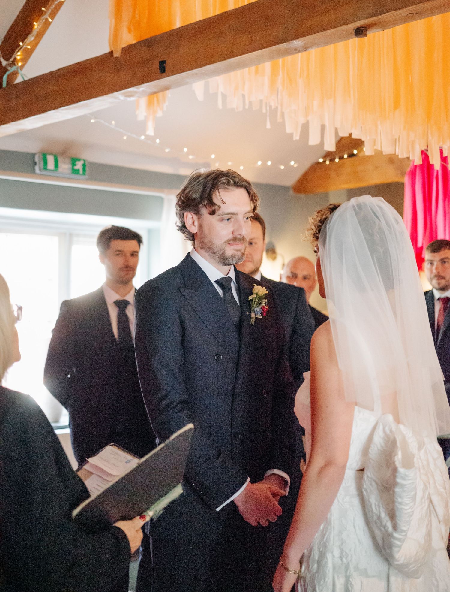 An intimate wedding ceremony moment under wooden beams with streaming natural light.