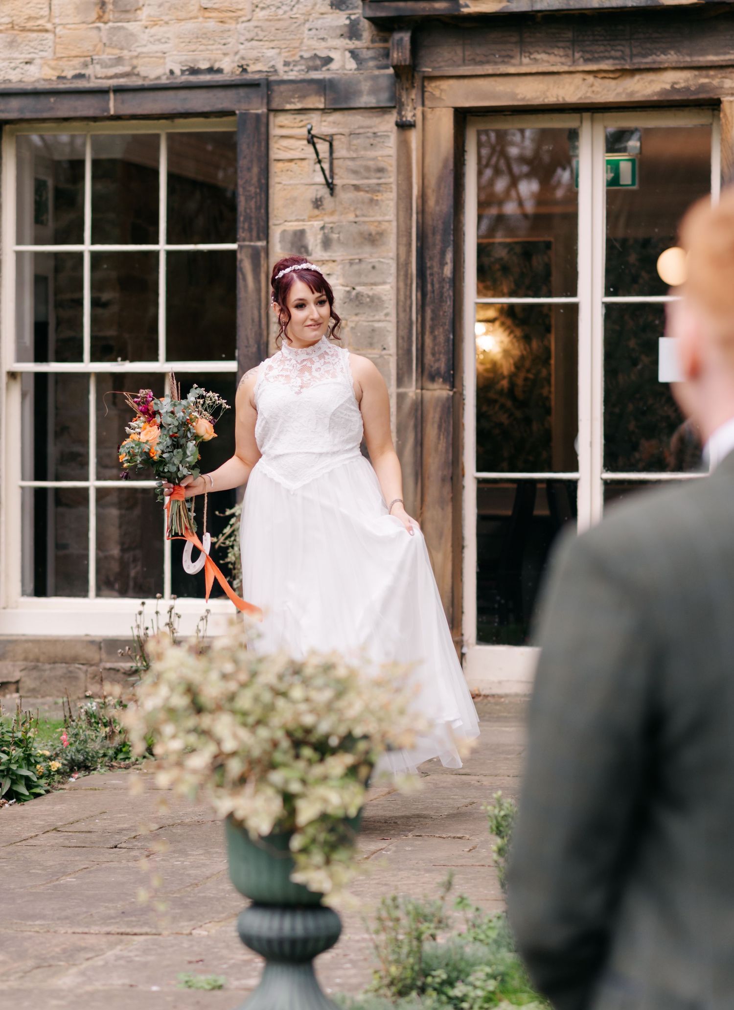 Elegant wedding scene at a historic stone building with large windows.