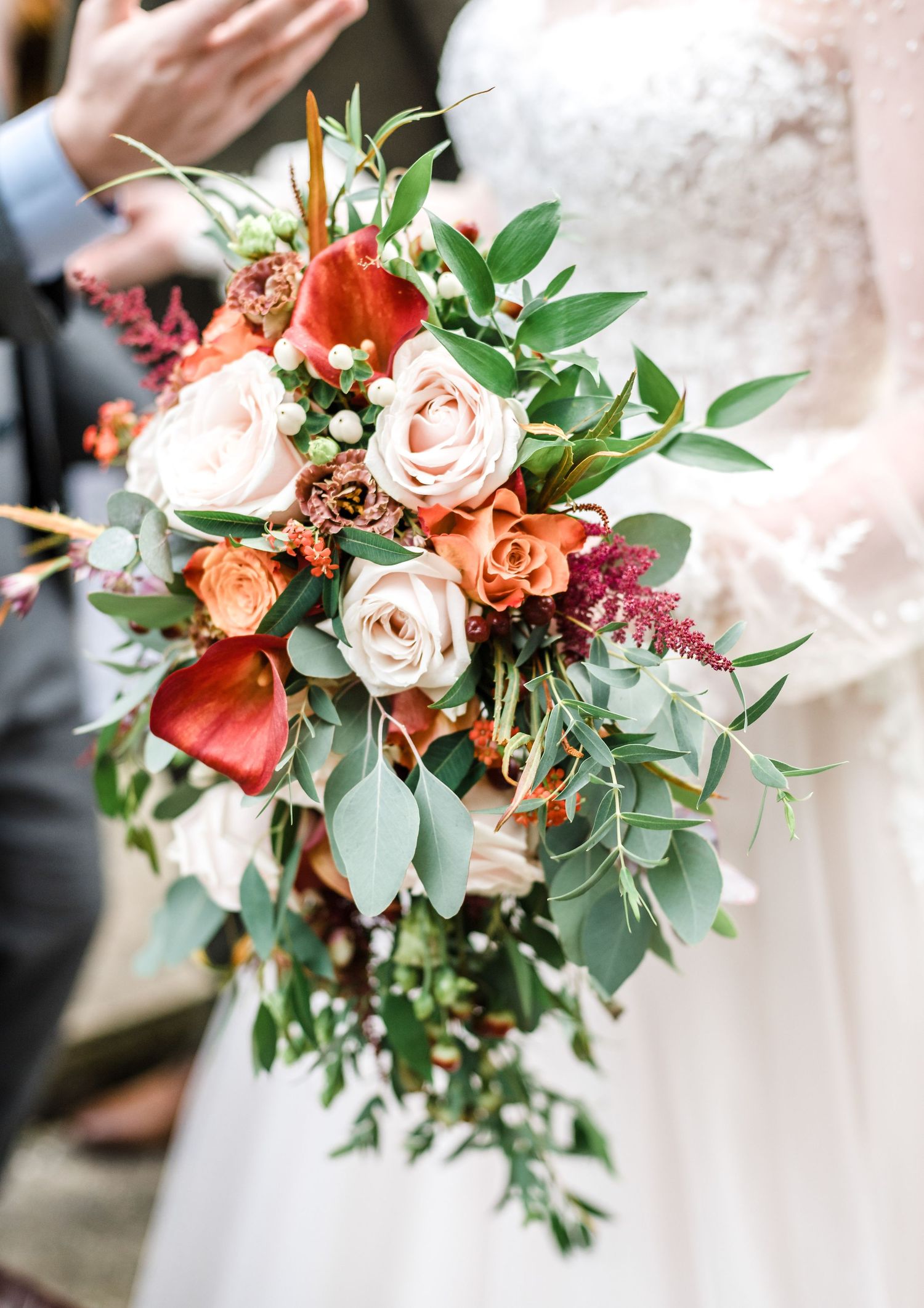 Beautiful bridal bouquet featuring coral and blush roses with eucalyptus greenery.