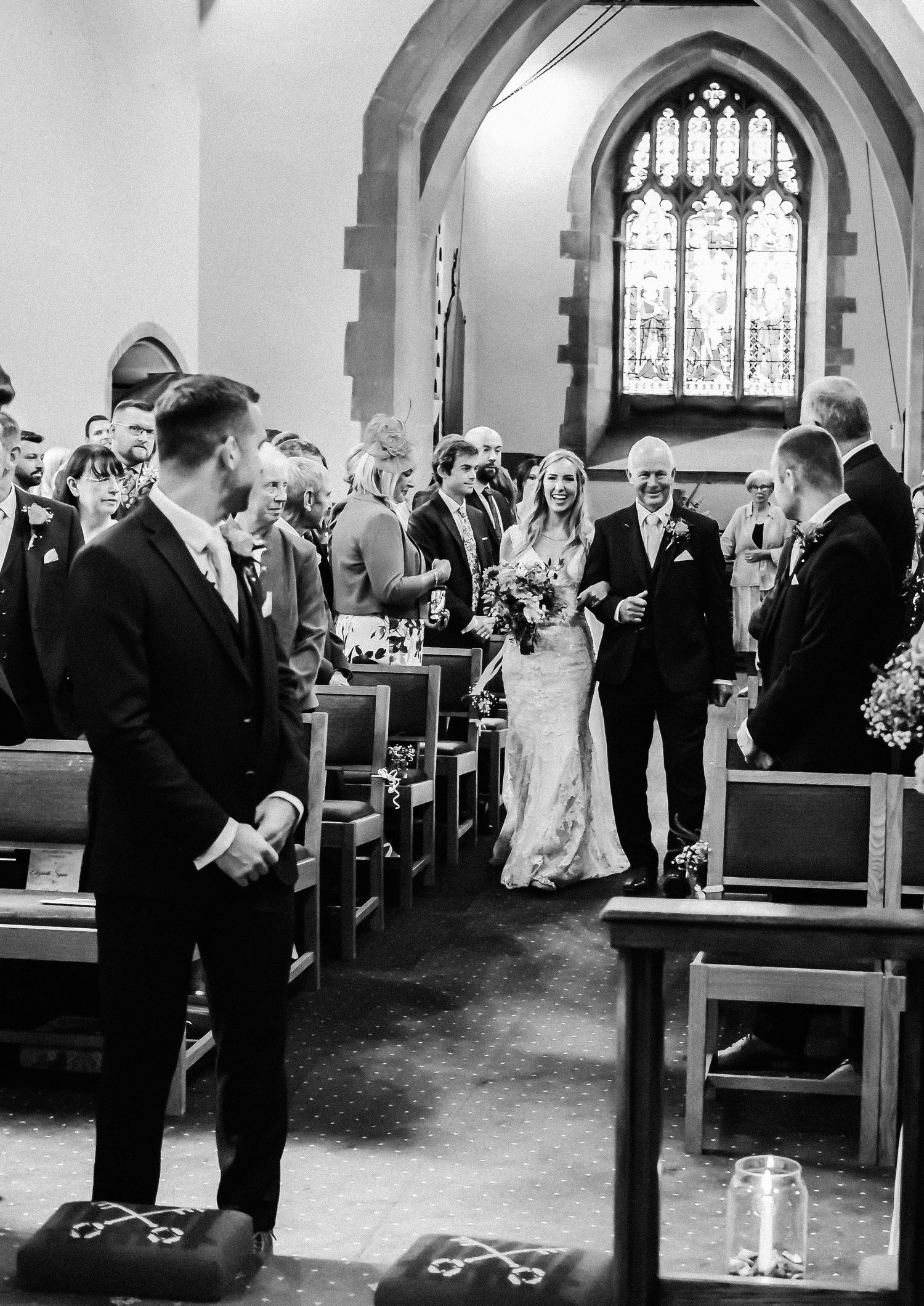 Black and white photo of traditional church wedding ceremony with stained glass windows.