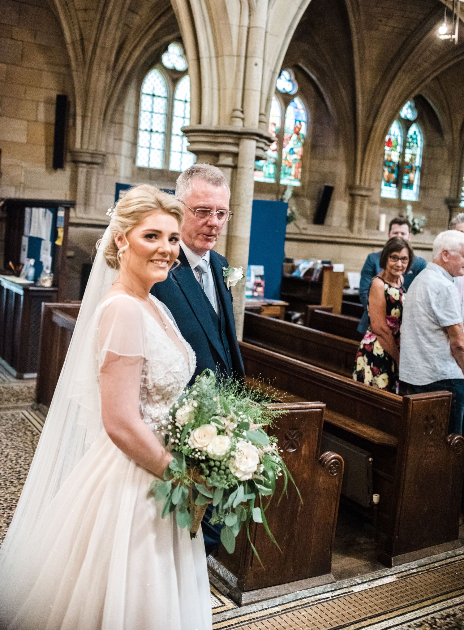A wedding ceremony in a historic church with gothic architecture and stained glass windows.