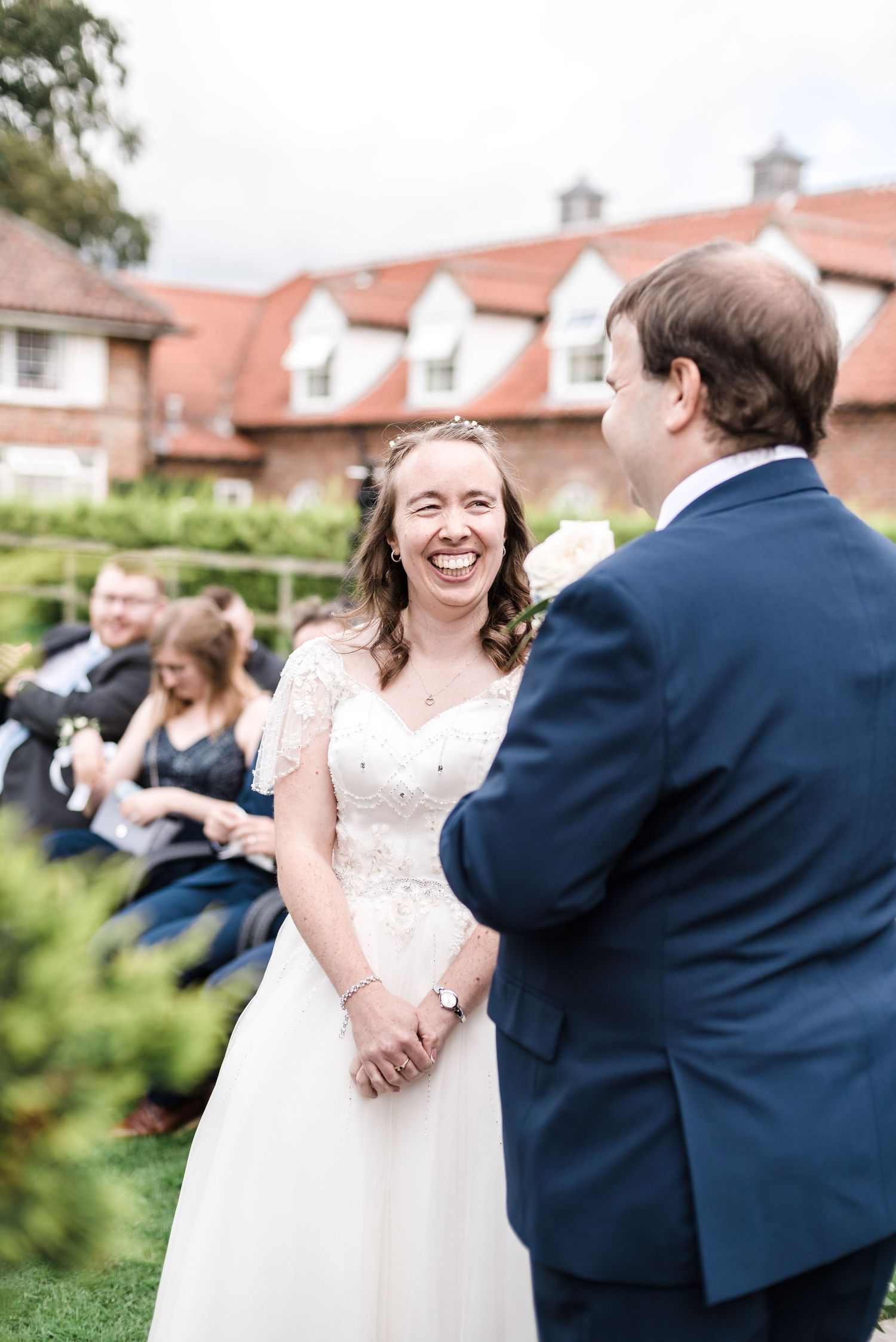 A candid wedding moment shared during an outdoor garden ceremony with guests seated nearby.