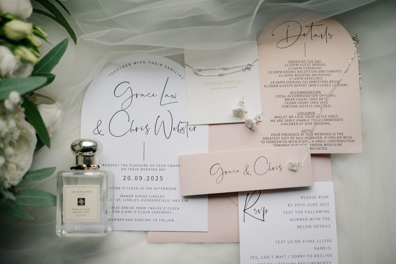 Elegant wedding invitation suite with blush pink and white cards nestled among green eucalyptus leaves.
