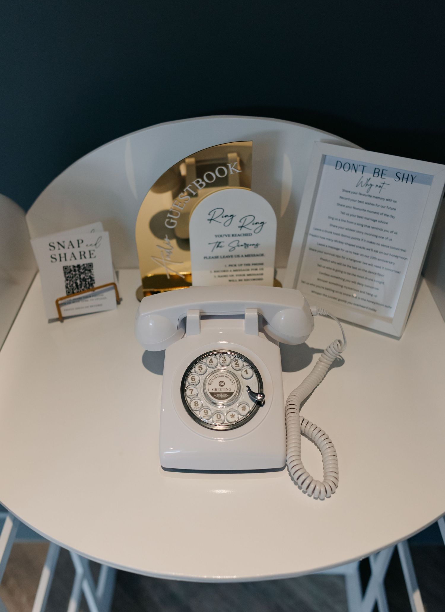 White rotary telephone and paper items displayed on curved white table surface.