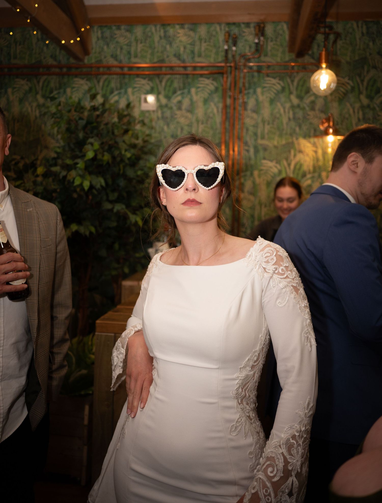 Stylish wedding reception scene with sunglasses and modern decor in an indoor garden setting.
