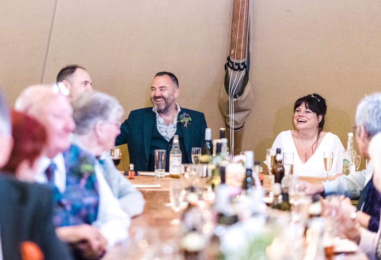 Wedding guests enjoying dinner conversation at a table set for a reception.