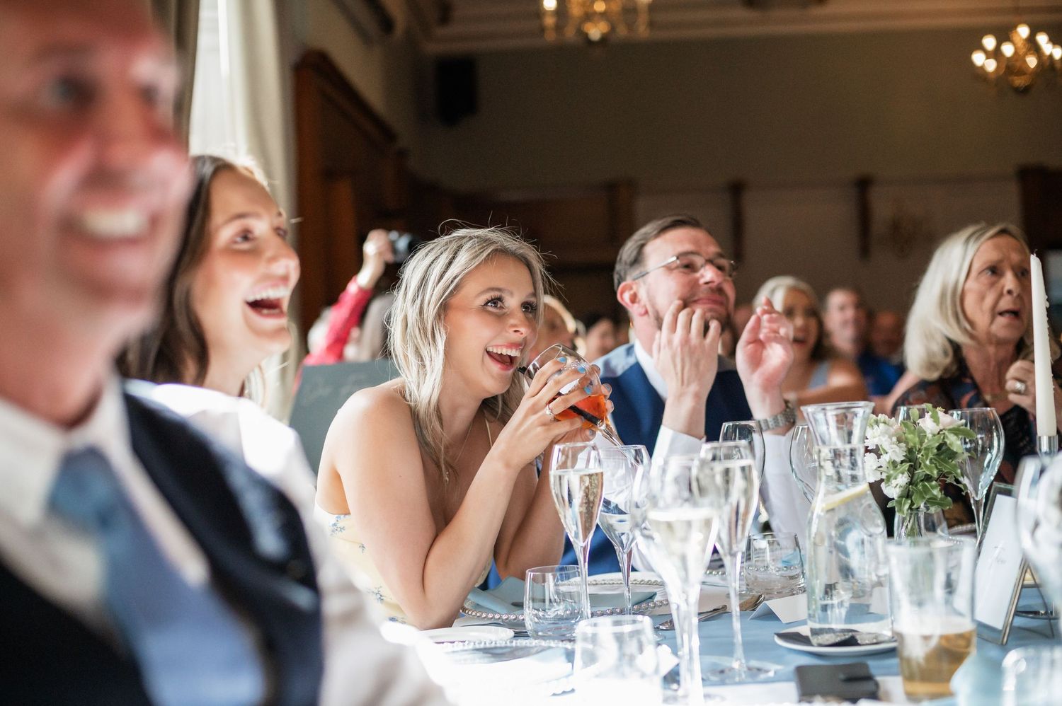 Wedding guests laughing and enjoying themselves at an elegant reception dinner.