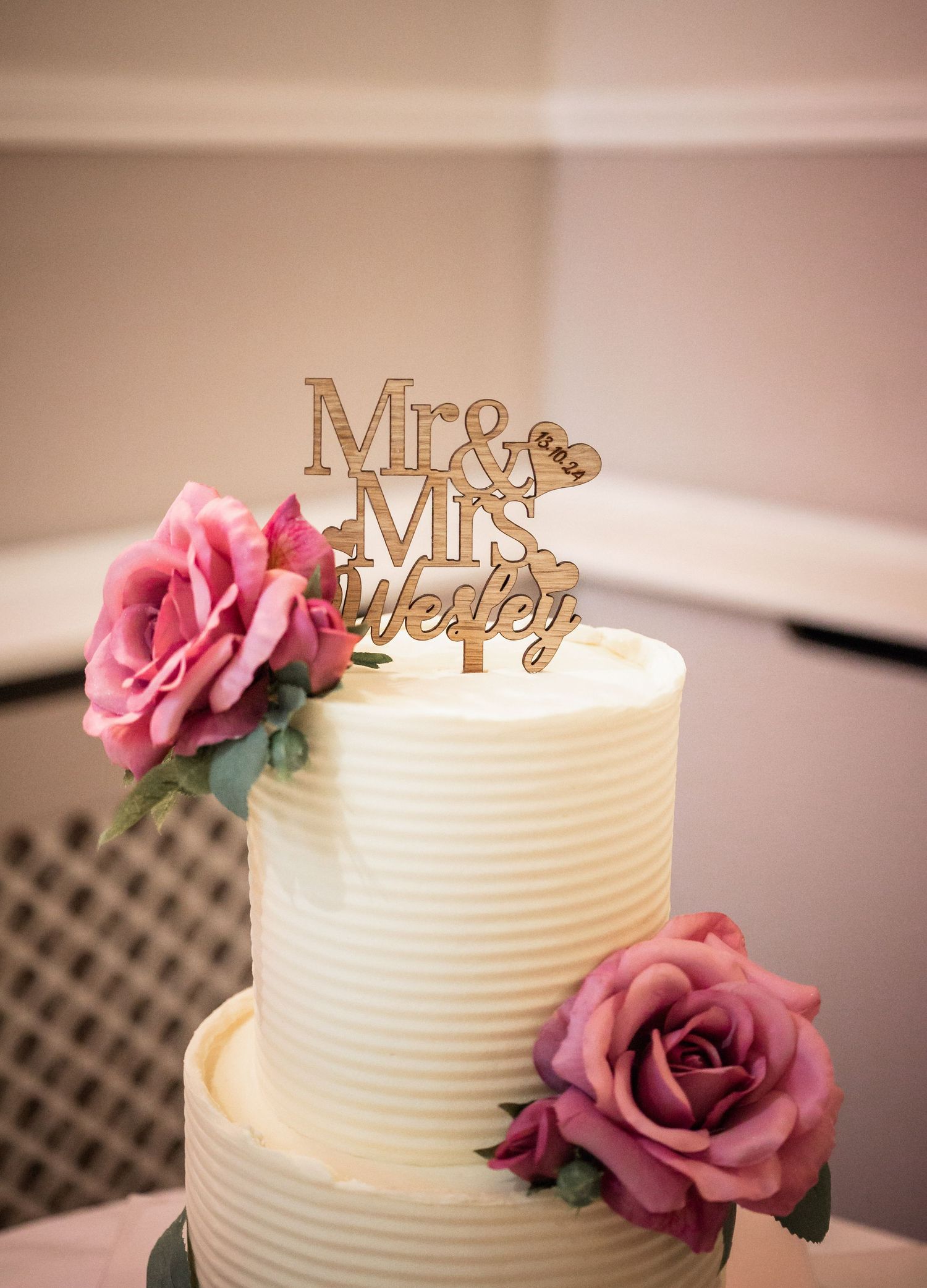 Wedding cake with textured buttercream frosting, pink roses and wooden Mr & Mrs topper.