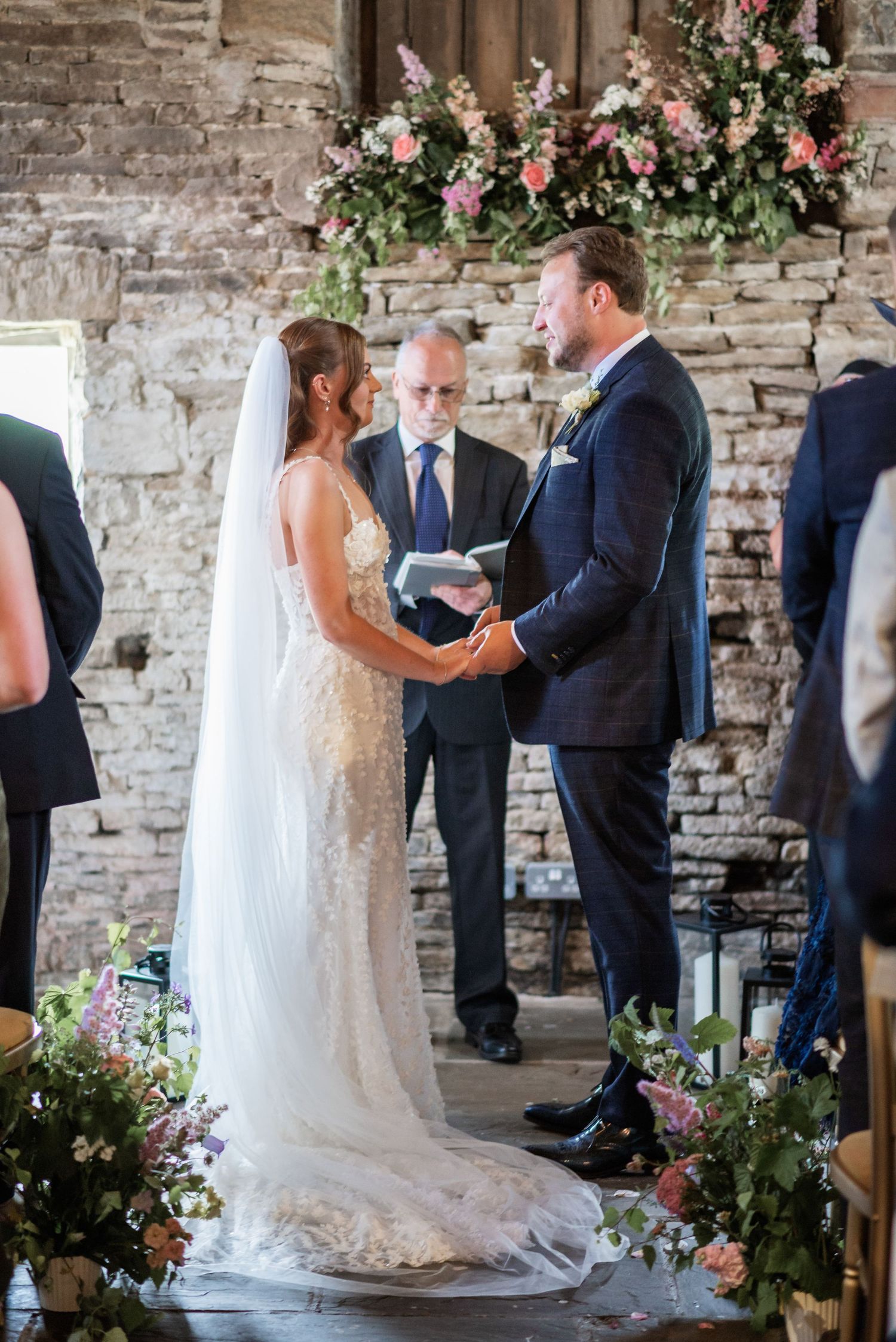 A romantic wedding ceremony in a rustic stone venue with floral decorations.