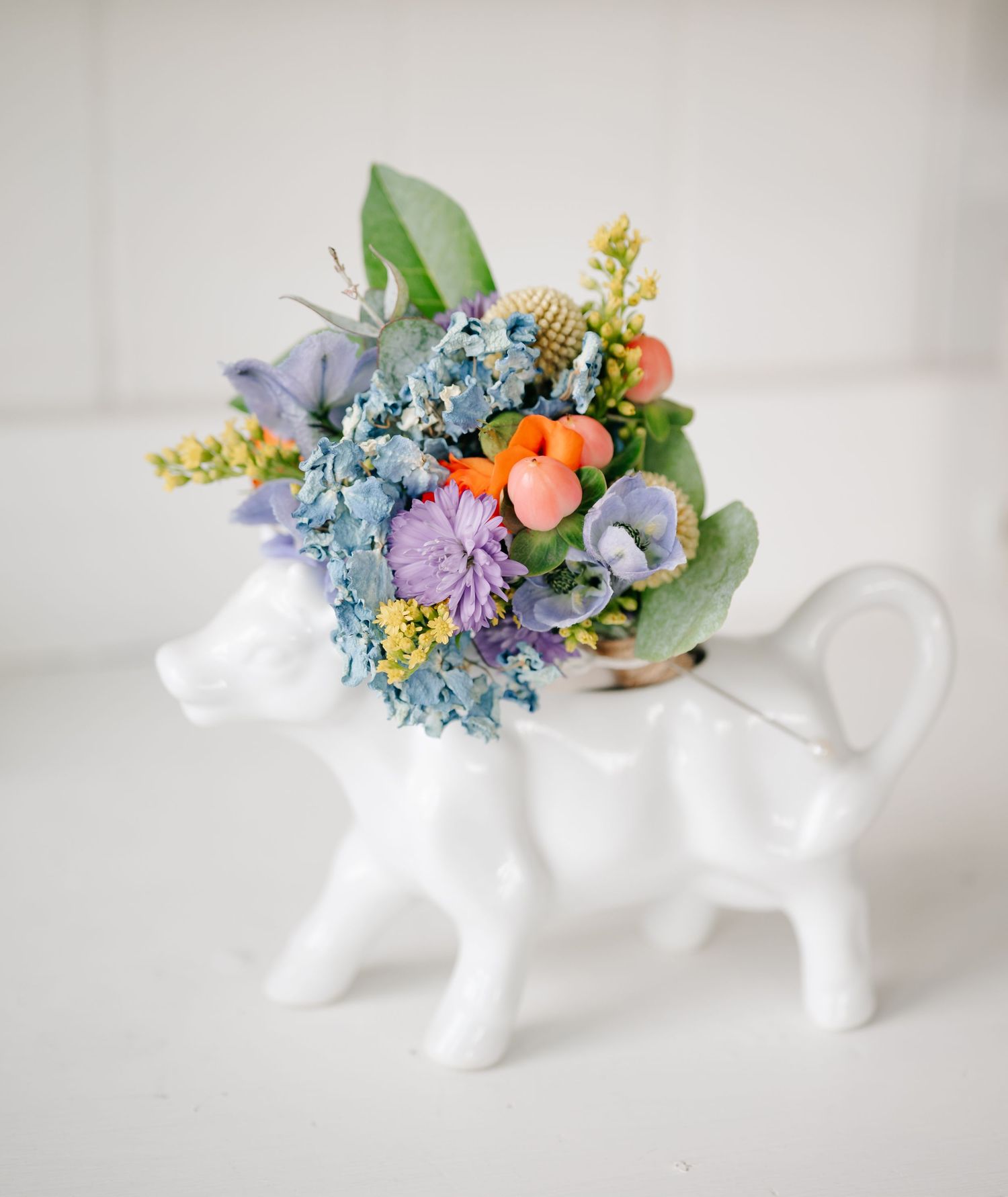 White ceramic teapots decorated with delicate blue and peach flowers arranged in a row against white background.