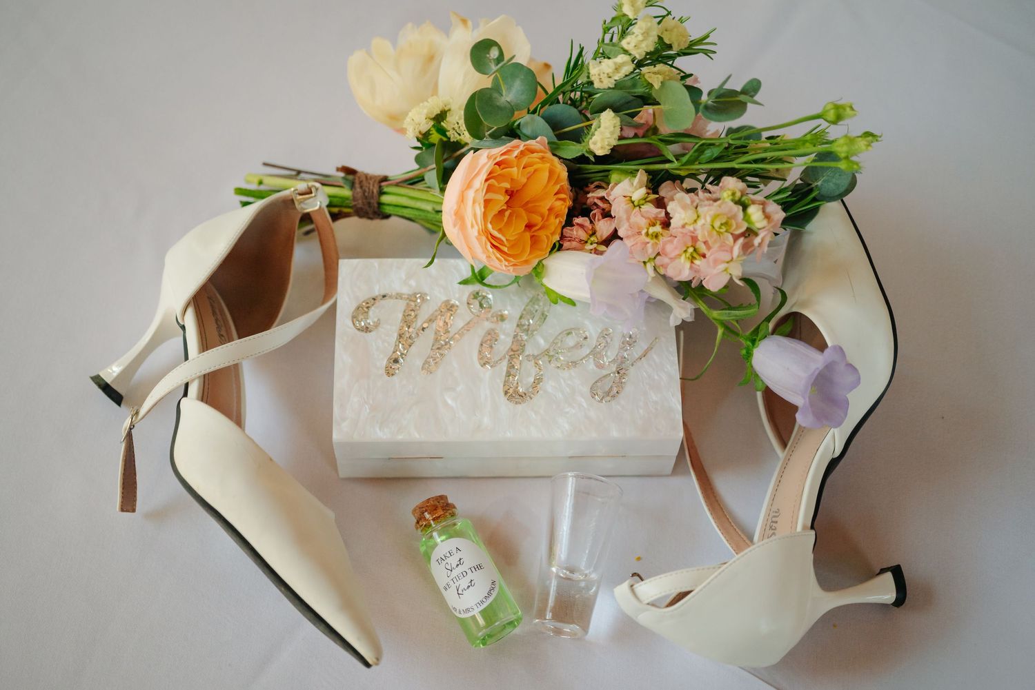 White wedding place cards with elegant calligraphy displayed alongside delicate peach and pink floral arrangements.