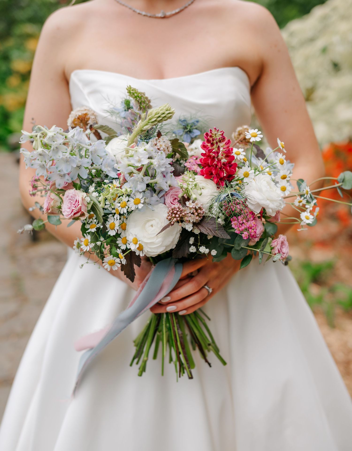 Four close-up shots of elegant wildflower wedding bouquets with white, pink and purple blooms against white dresses.