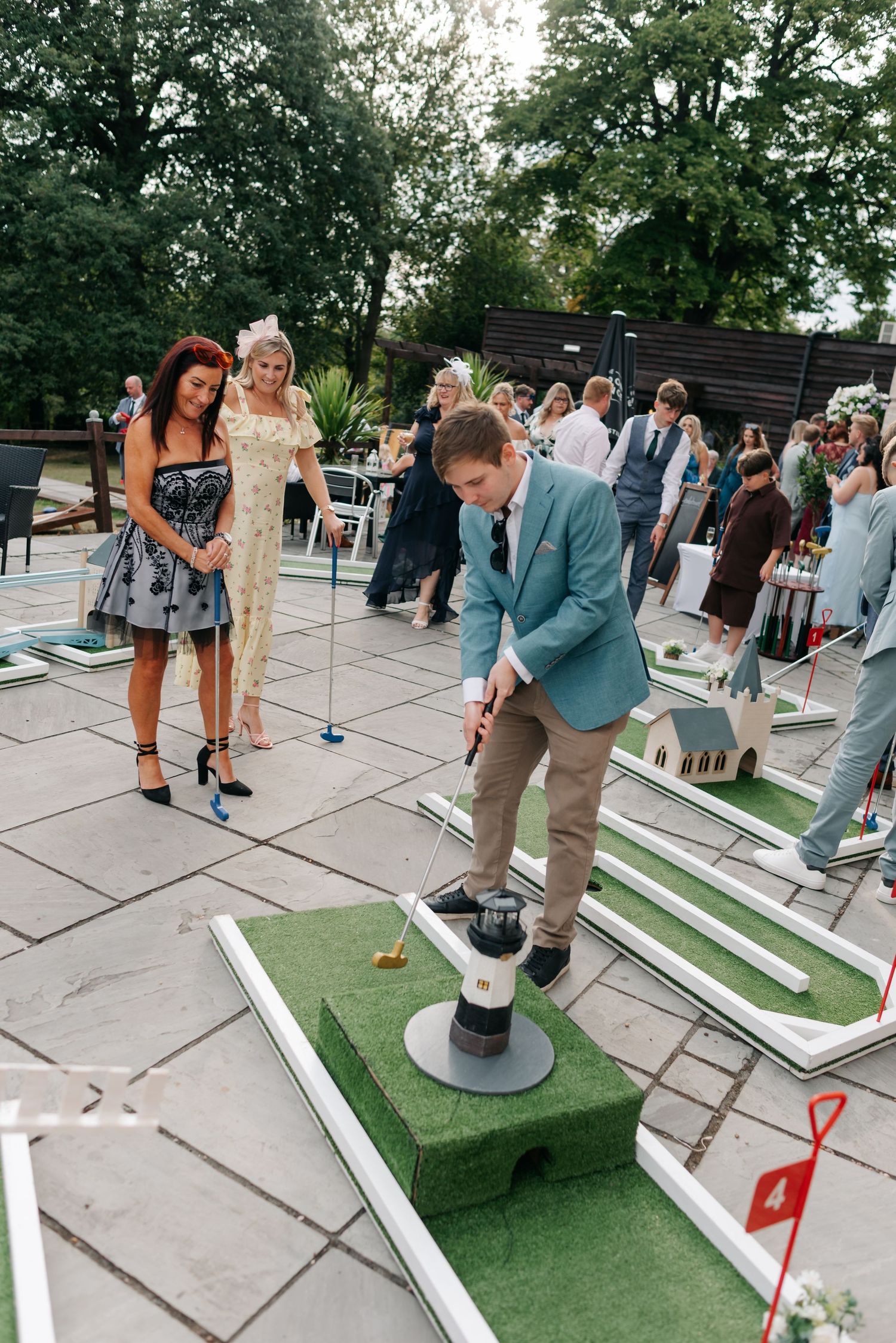 Wedding guests enjoy playing miniature golf on a patio entertainment setup.