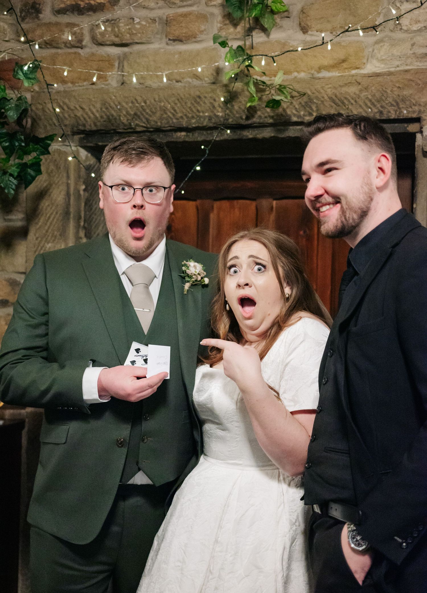 Three people react with exaggerated surprised expressions during a wedding celebration.