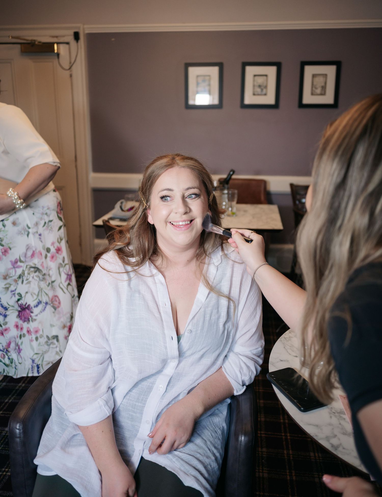 A candid moment during bridal preparations as makeup is being applied in a cozy indoor setting.