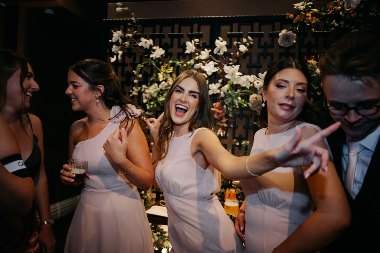 Wedding party dancing and celebrating during an evening reception with floral decorations.