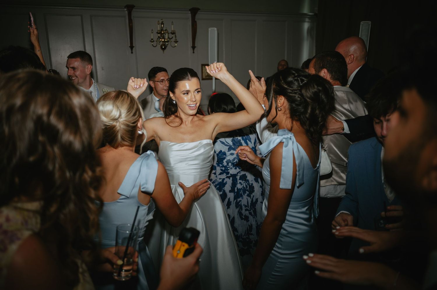 Dark and moody reception scene with dancing wedding guests in silhouette.