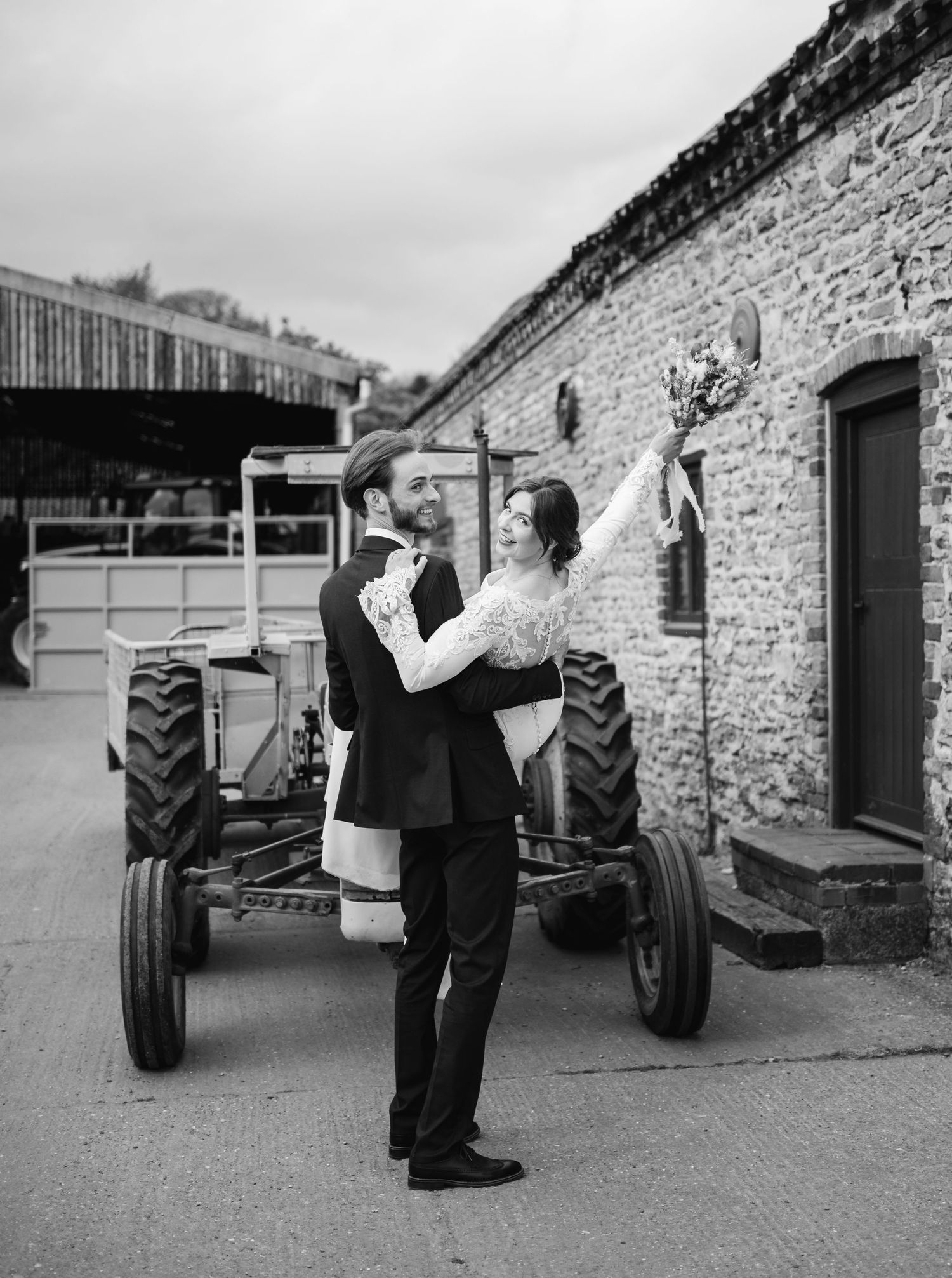 Black and white sequence of groomsmen taking shots in front of vintage tractors.