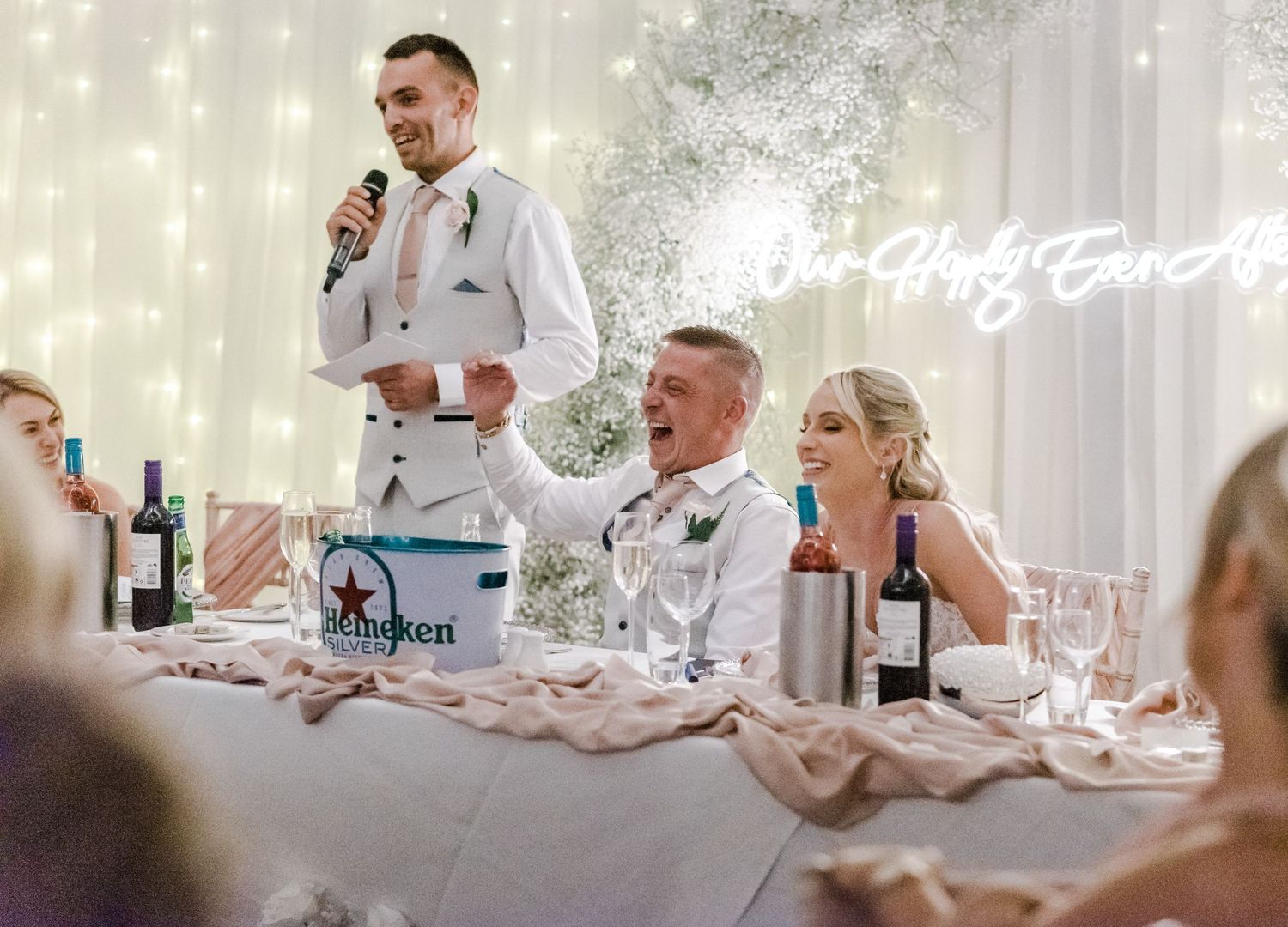 Wedding reception featuring toasts and speeches in a room decorated with twinkling lights.