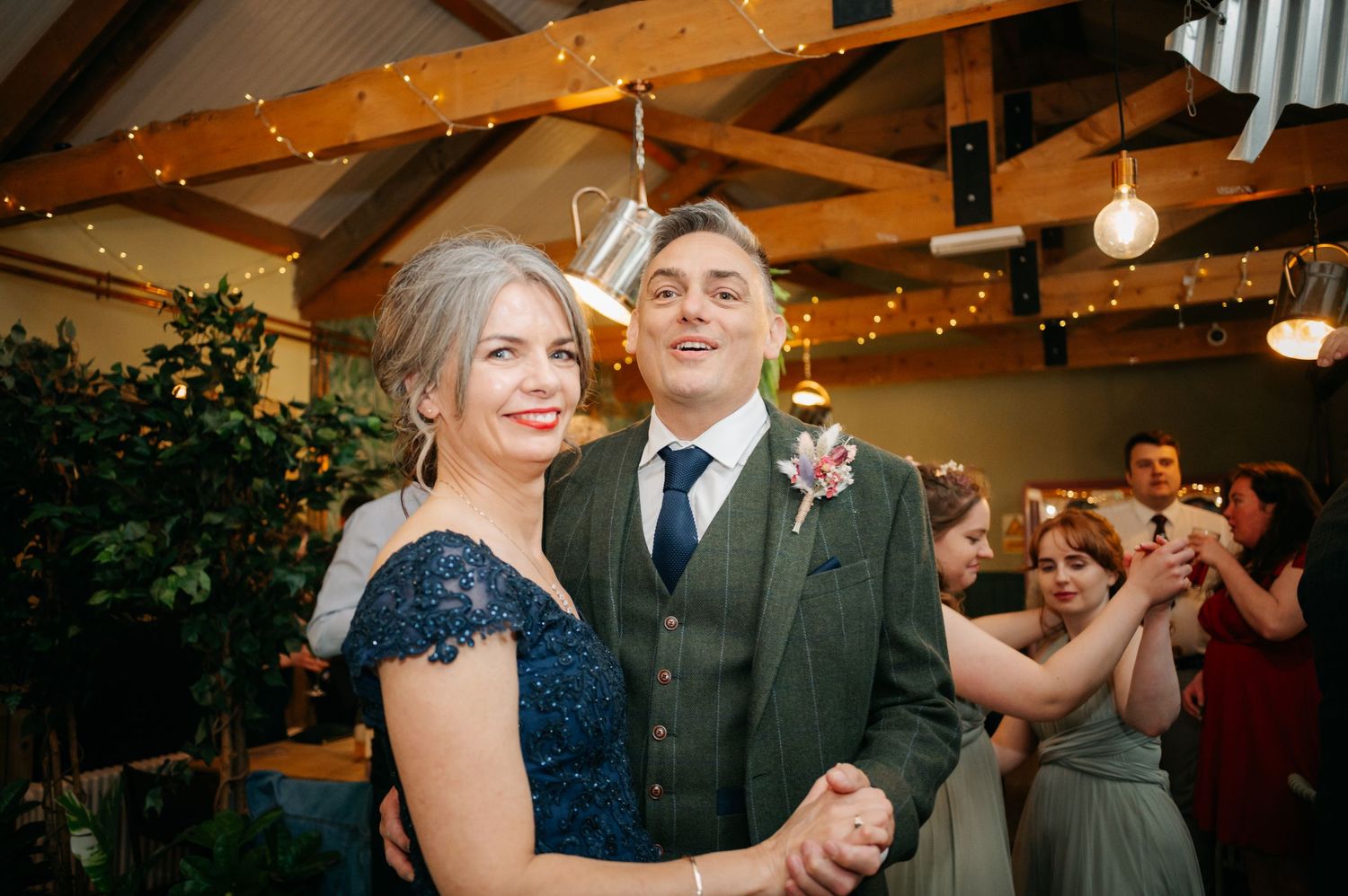 Couples dancing together at evening wedding reception under warm indoor lighting.