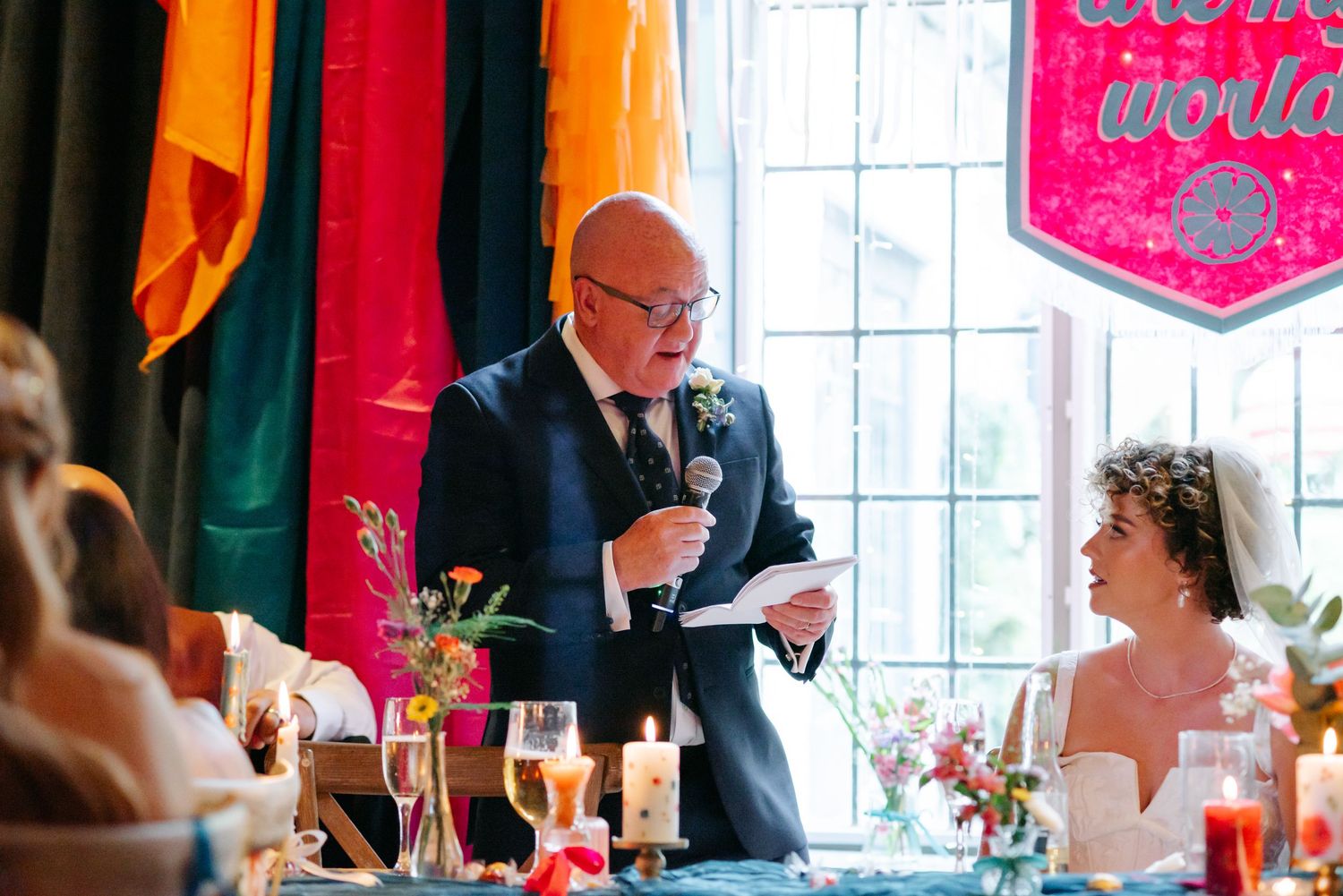 Wedding reception scene with pink decorations and champagne glasses on tables.