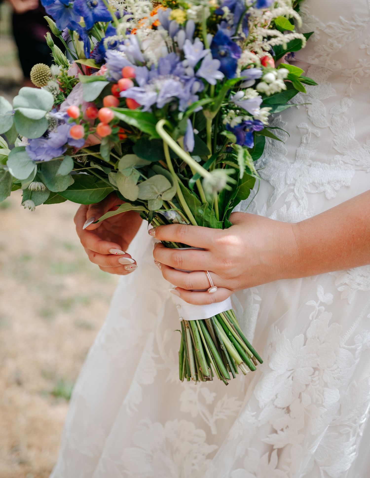 Bridal bouquet featuring blue, yellow and white flowers with eucalyptus leaves.