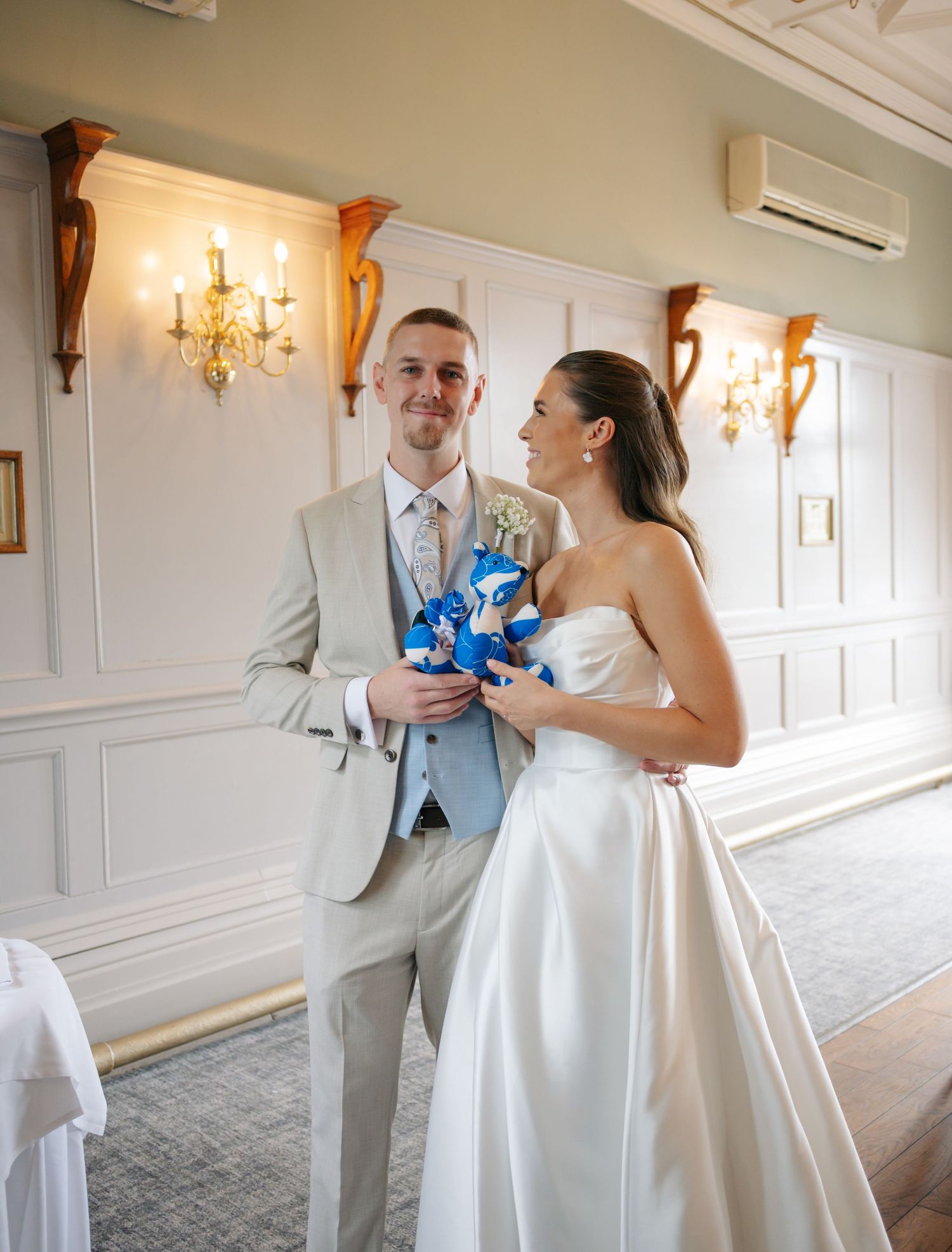 Wedding couple dancing and twirling in an elegant indoor venue with white paneled walls.