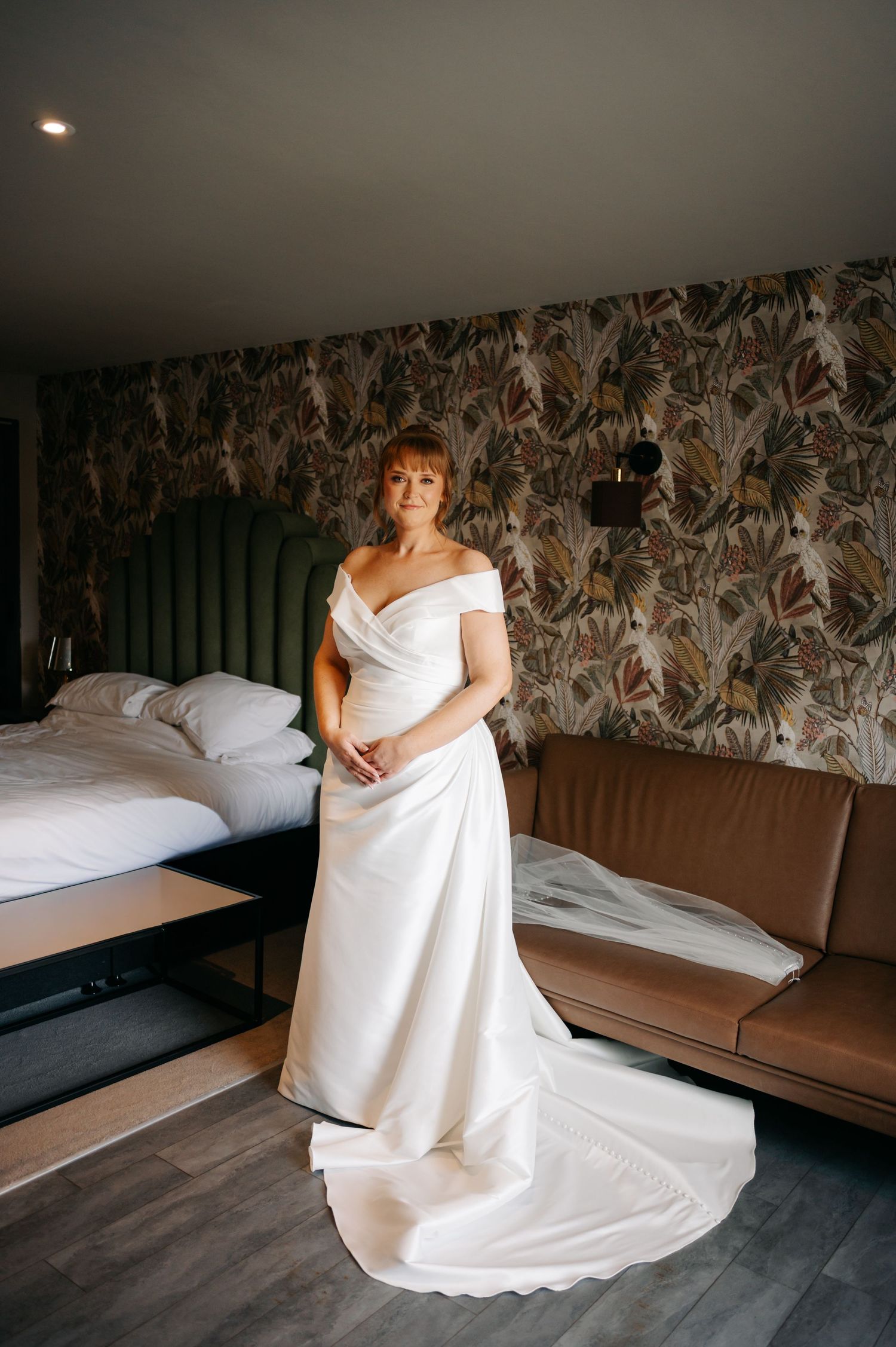 Bridal preparation scene in a room with modern floral wallpaper and brown furniture.