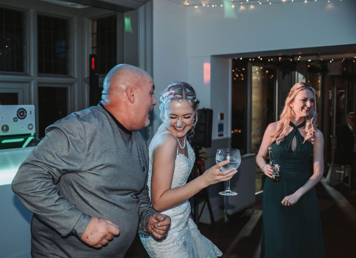 Lively dancing moment during wedding reception with string lights overhead.