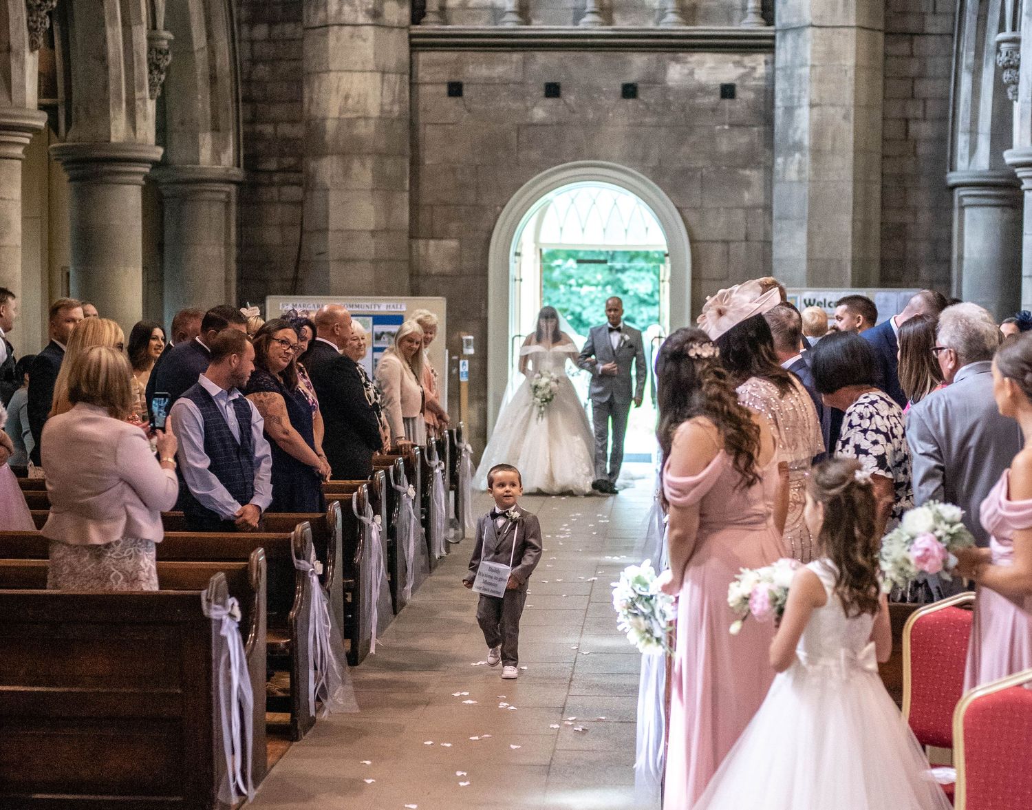 Wedding guests watch as the couple walks down the aisle in a historic stone church.