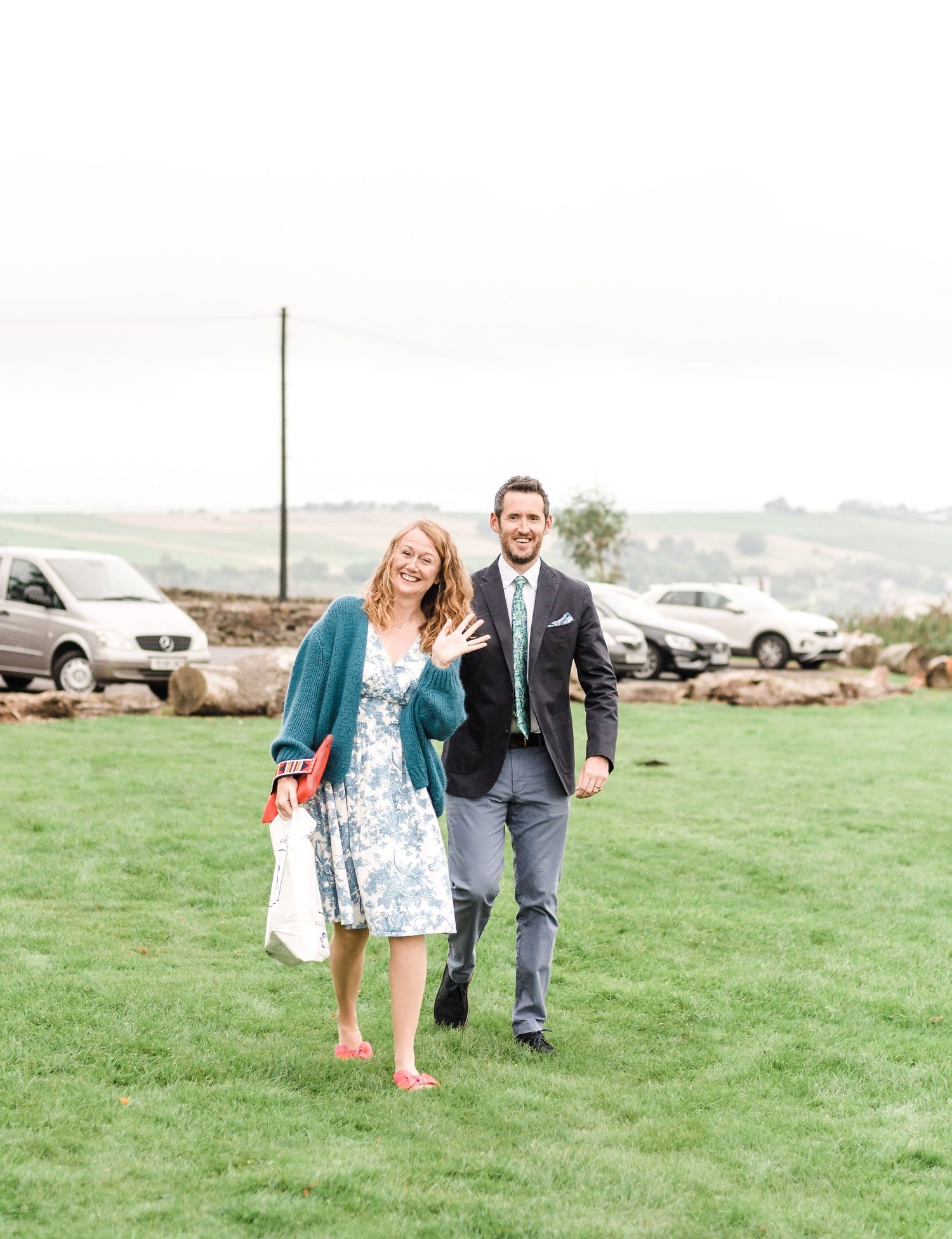Joyful wedding guests celebrating on a green lawn with festive attire.